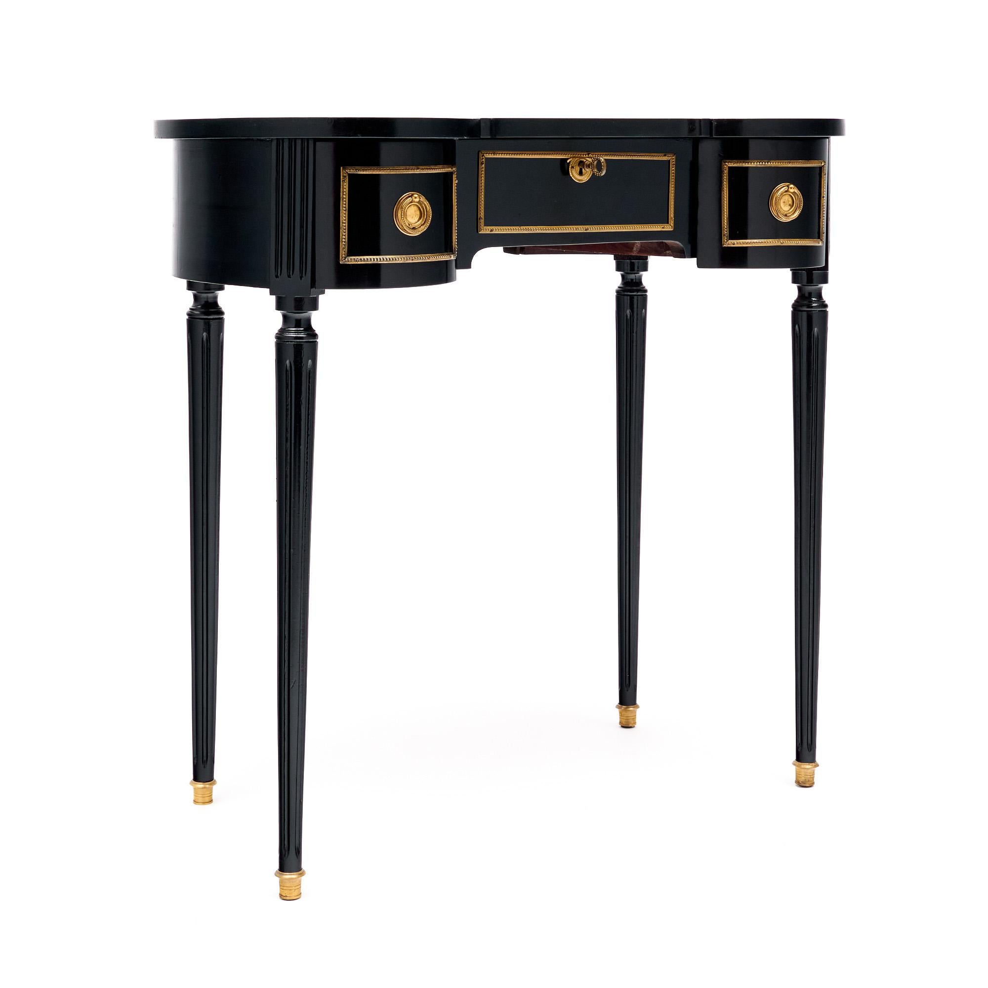 Vanity from France in the Louis XVI style. This piece is made of solid wood construction, primarily mahogany, that has been ebonized and finished with a lustrous French polish finish of museum quality. The table has a beautiful unique shape and