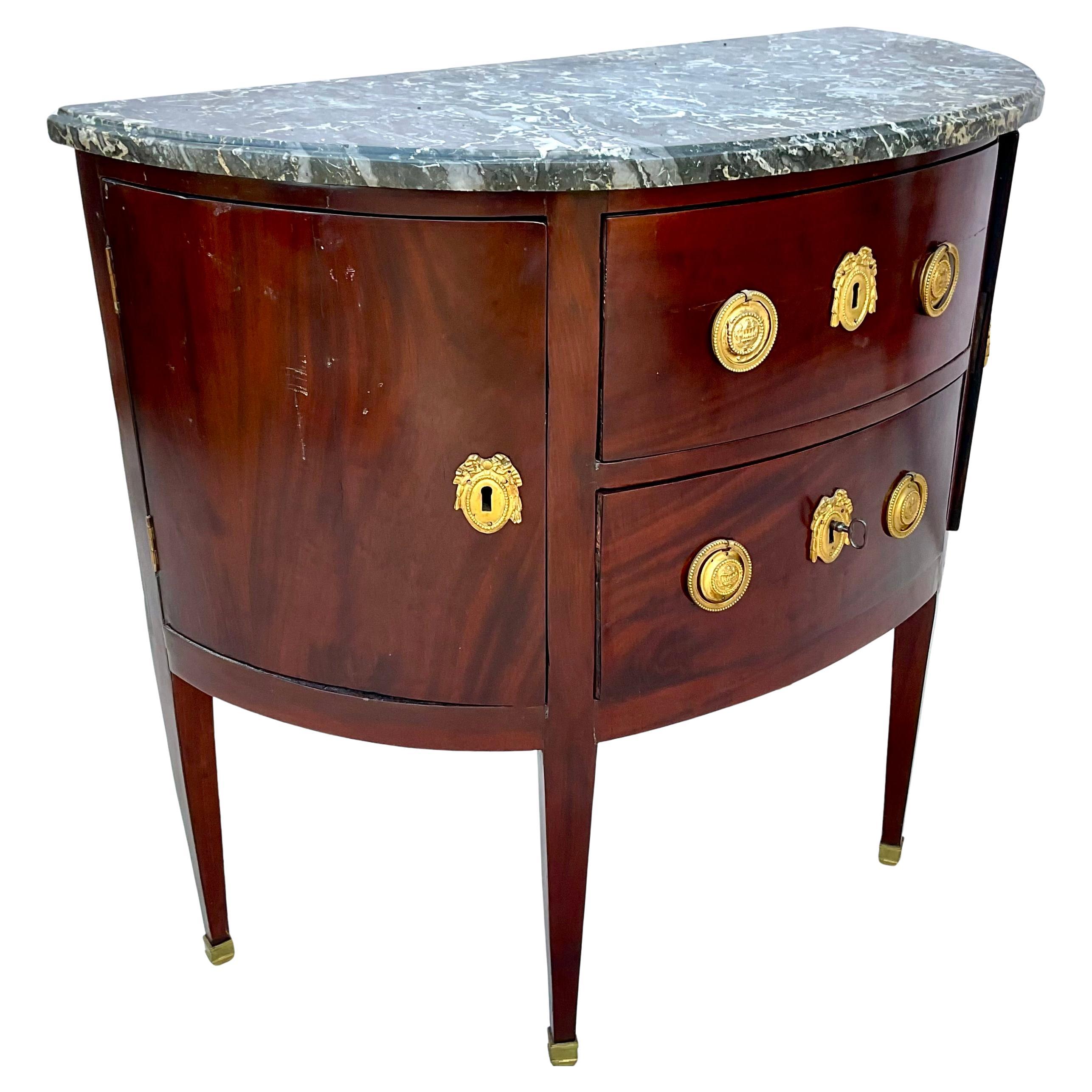 Late 18th Century Louis XVI French Mahogany Demilune Commode with original Black Marble Top. Commode features two drawers with brass ring pulls, the drawers are framed by two side doors that open for further storage. The Commode has a graceful