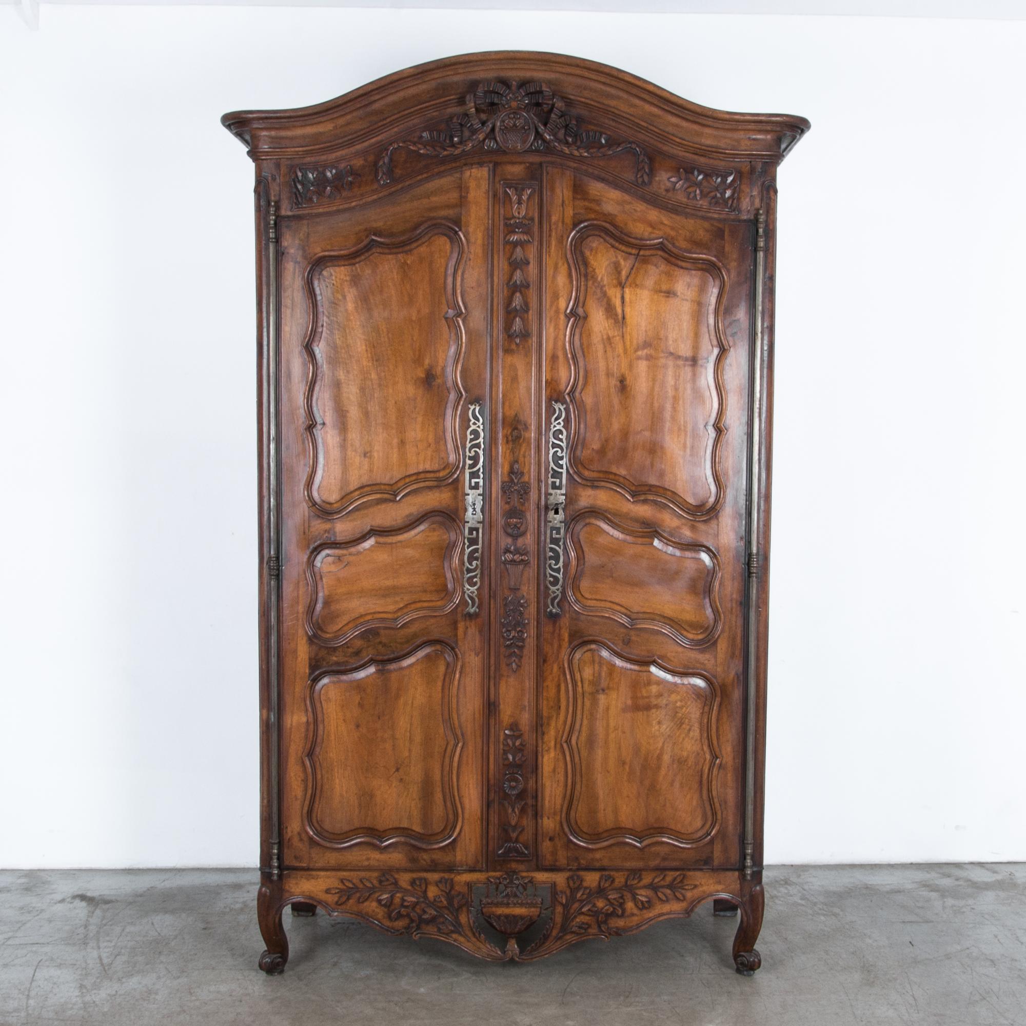 Embellished with original iron hardware and distinctive twin hearts decoration, this elaborately carved wardrobe comes from late 18th century, France. Embellishments recall the local landscape, an ample inspiration for provincial French decorators,