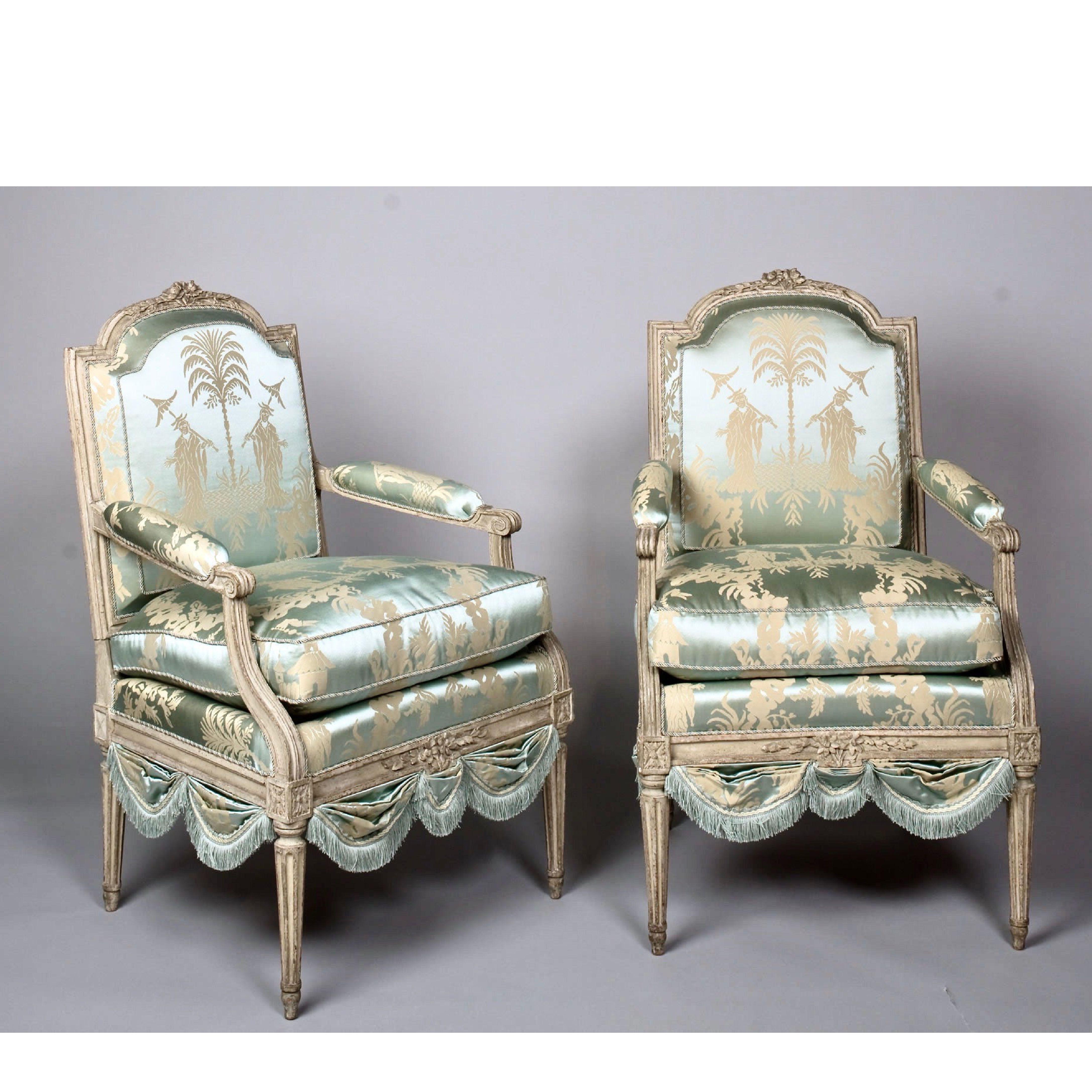 Louis XVI French silk armchair, Claude II Sené Fauteuil a la Reine, early 1780s. Arched, padded back with stylized flowerhead hand carved topsail, similarly poetic hand carved seat rail. Raised on gracefully tapering, fluted legs. Reupholstered in
