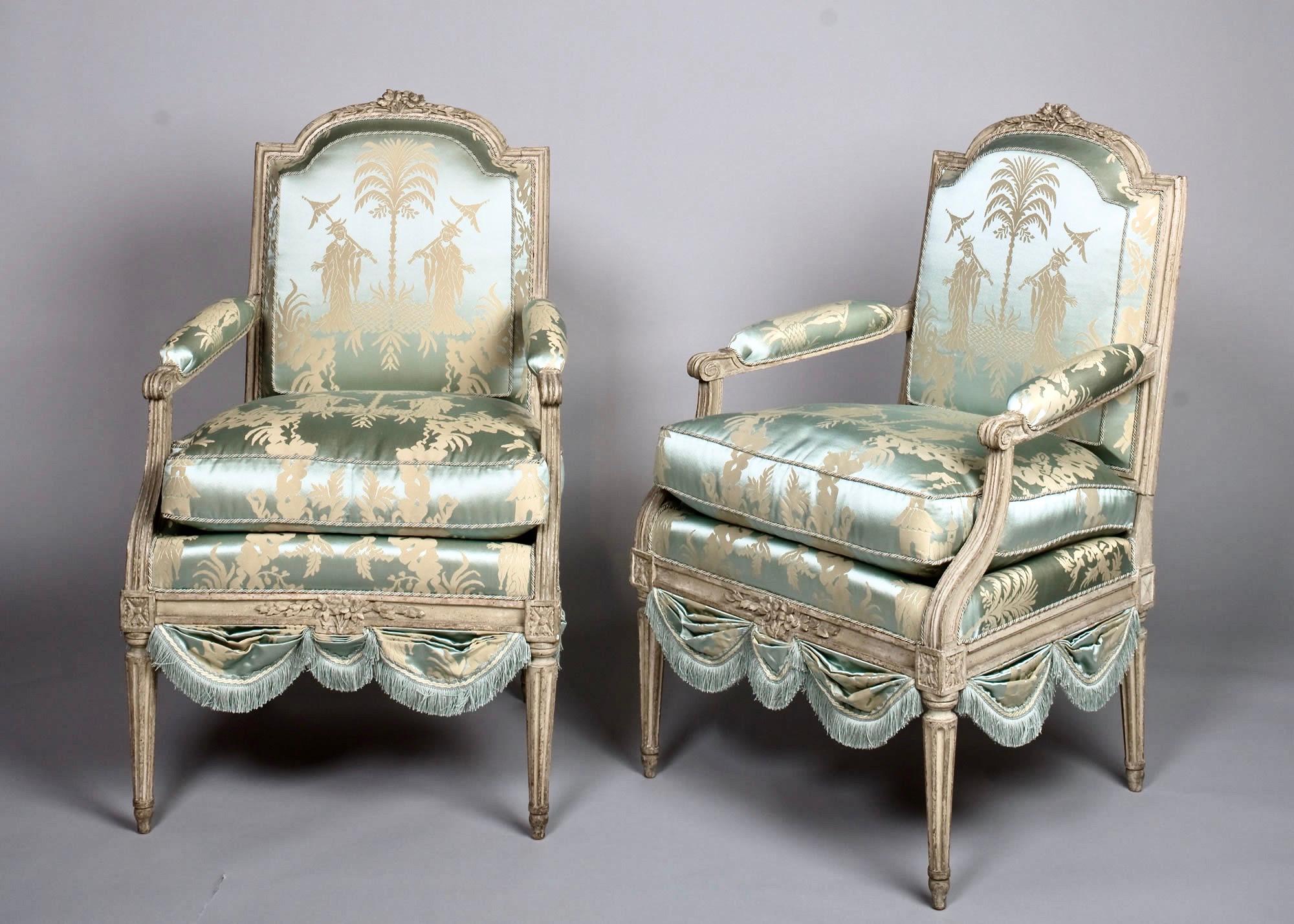 Louis XVI French silk armchair, Claude II Sené Fauteuil a la Reine, early 1780s. Arched, padded back with stylized flowerhead hand carved topsail, similarly poetic hand carved seat rail. Raised on gracefully tapering, fluted legs. Reupholstered in