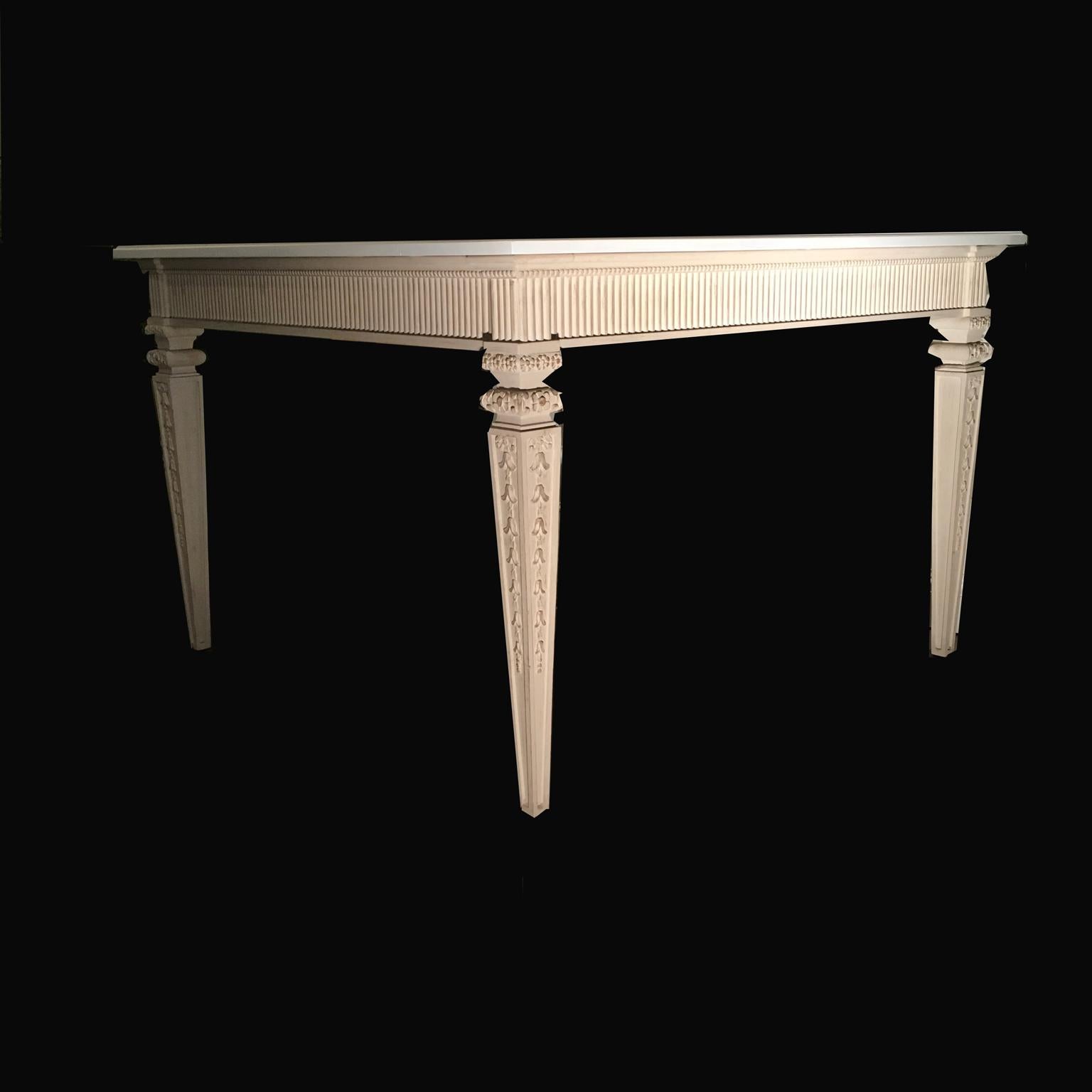 This is an elegant French dining table in solid oak, with rich hand-carved details on the legs. It has a double colors: the top is hand lacquered in white egg color and the four legs with the band under the top is hand lacquered in ivory color. This
