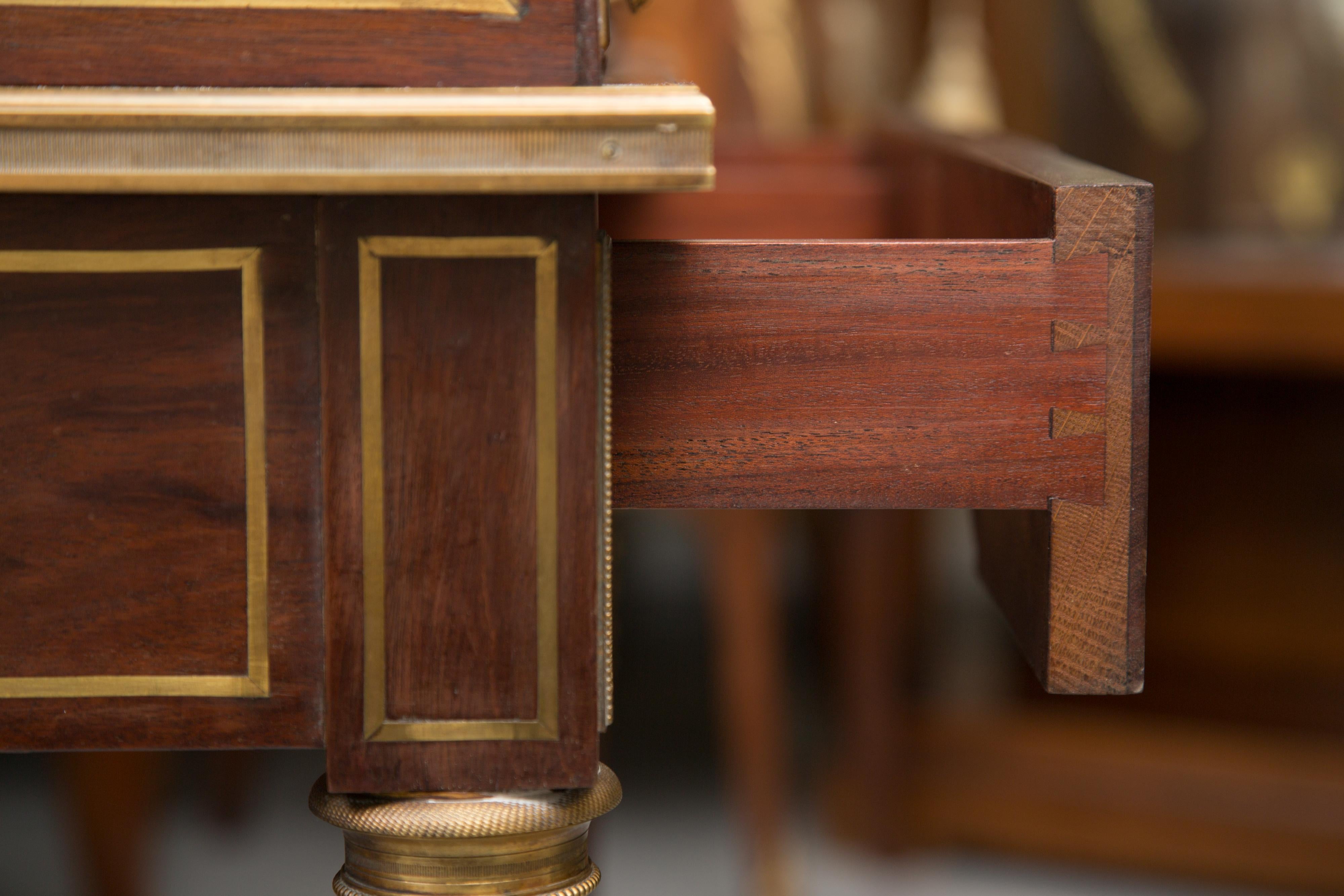 This is a handsome mahogany cylinder bureau de dame of delicate proportions. The hand selected mahogany is decorated with gilt bronze. The top of the desk has a gallery and three small drawers. The cylinder opens to reveal a pull out writing surface