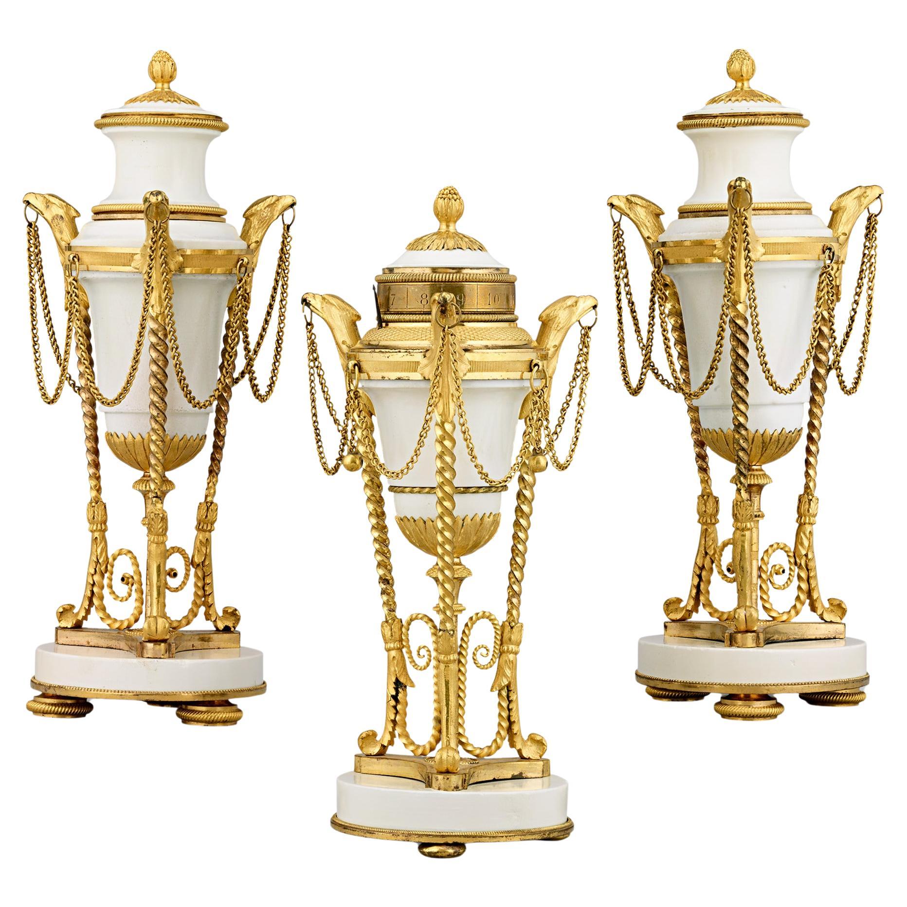 Louis XVI Gilt Marble Cassolettes And Clock For Sale