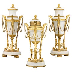 Louis XVI. Cassolettes und Uhr aus vergoldetem Marmor
