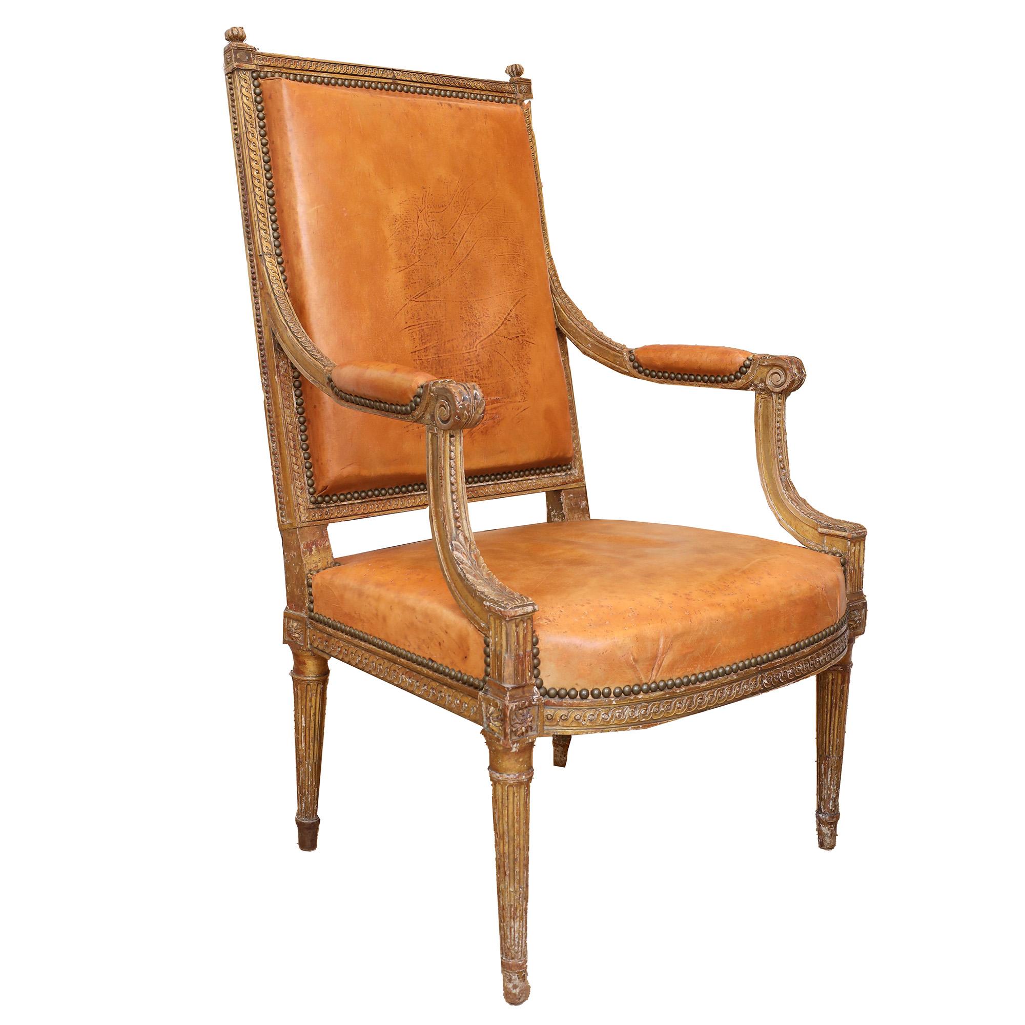 Carved distressed giltwood armchairs with leather upholstery, from circa 1790.
