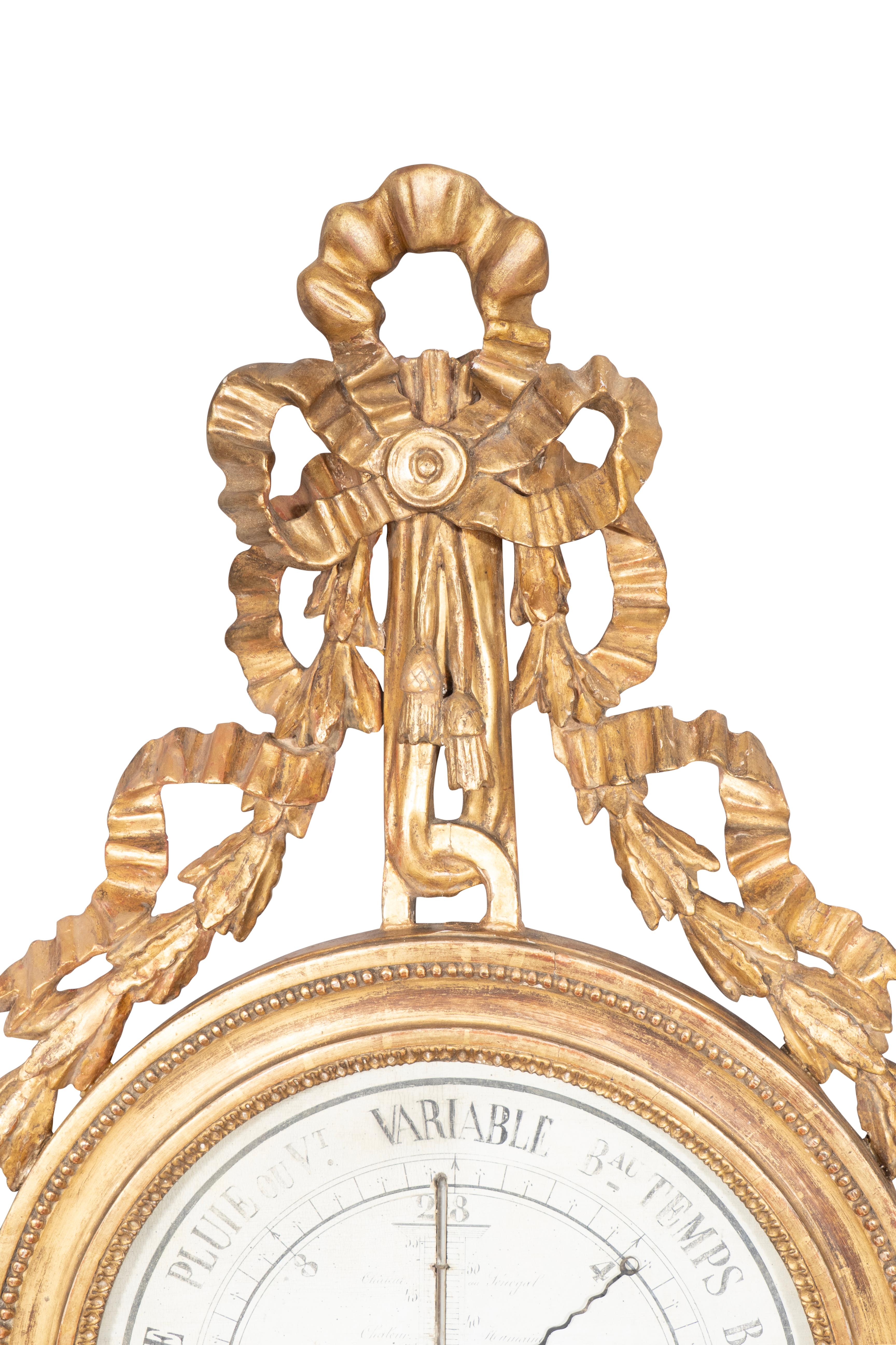 Mit Band und Schleife geschnitzt und schleppende Glocke Blume über dem Barometer Zifferblatt. Das Zifferblatt mit grisaillegemalten Herstellerangaben und Zeigern in einem runden Rahmen aus Goldholz. Mit einer Schleife am Sockel abschließend.