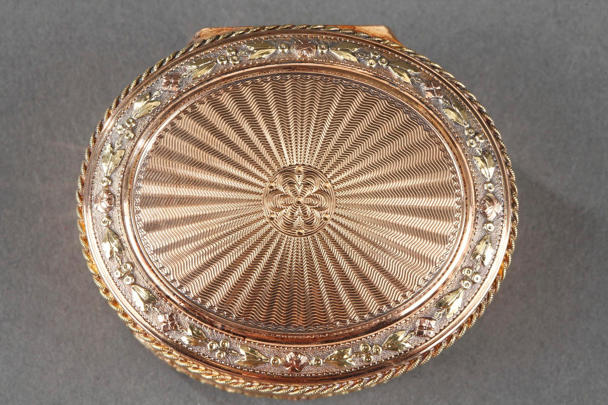 Val gold snuff box. The hinged lid is decorated with a radiant guilloche pattern and surrounded by a frieze of roses and leaves in an amati background. The body of the box also has wave guilloche pattern panels interspersed with a flower