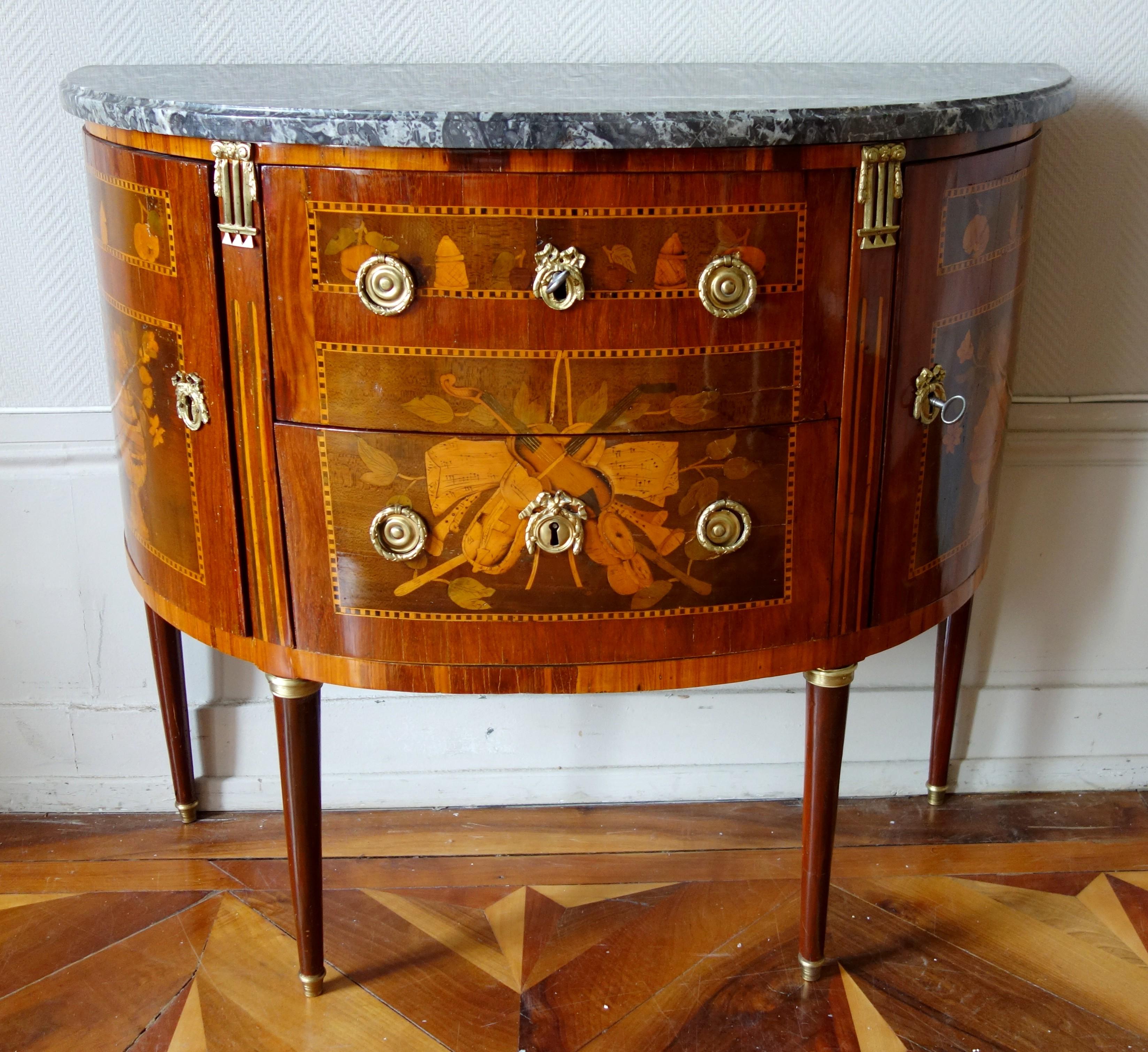 Antique French Louis XVI half-moon-shaped marquetry commode / chest of drawers.

18th century luxurious production : beautiful marquetry model with musical trophies, vases of flowers, fruits, everyday accessories (tea box ...) patterns on the