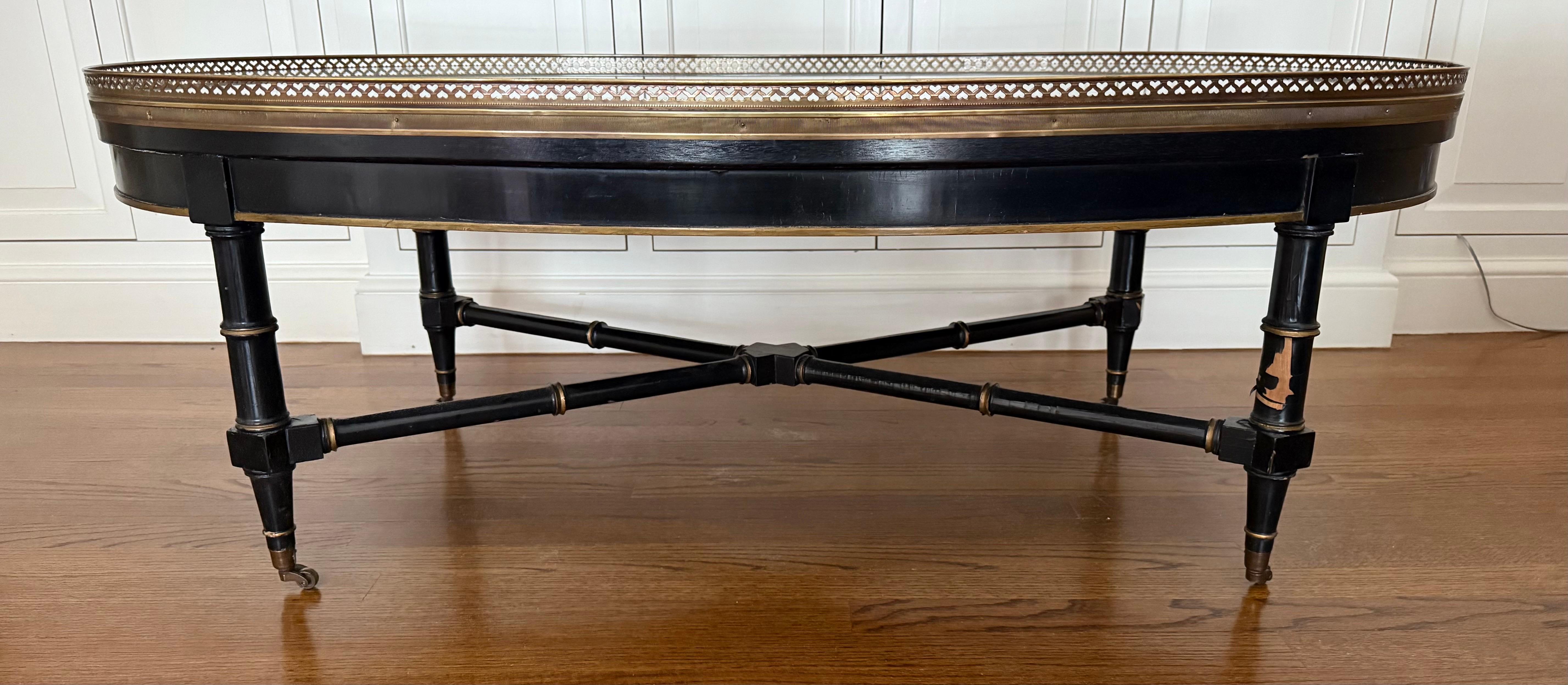 Magnifique table de cocktail ovale de style Louis XVI de la Maison Jansen avec galerie en laiton et couleurs noir et or. La garantie de rehausser chaque pièce qu'il habite ! Pourquoi ne pas posséder le meilleur ?