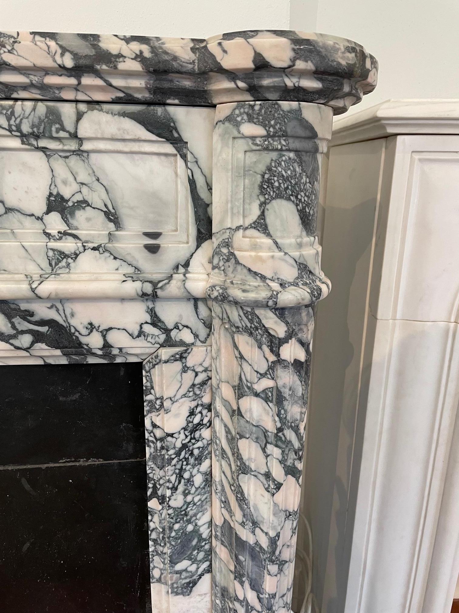 A very elegant French Louis XVI style fireplace in Breccia marble. The serpentine frieze with fluting of arcaded design. The fluted jambs of rounded form with square paterae end blockings above. A fine copy of an original piece.