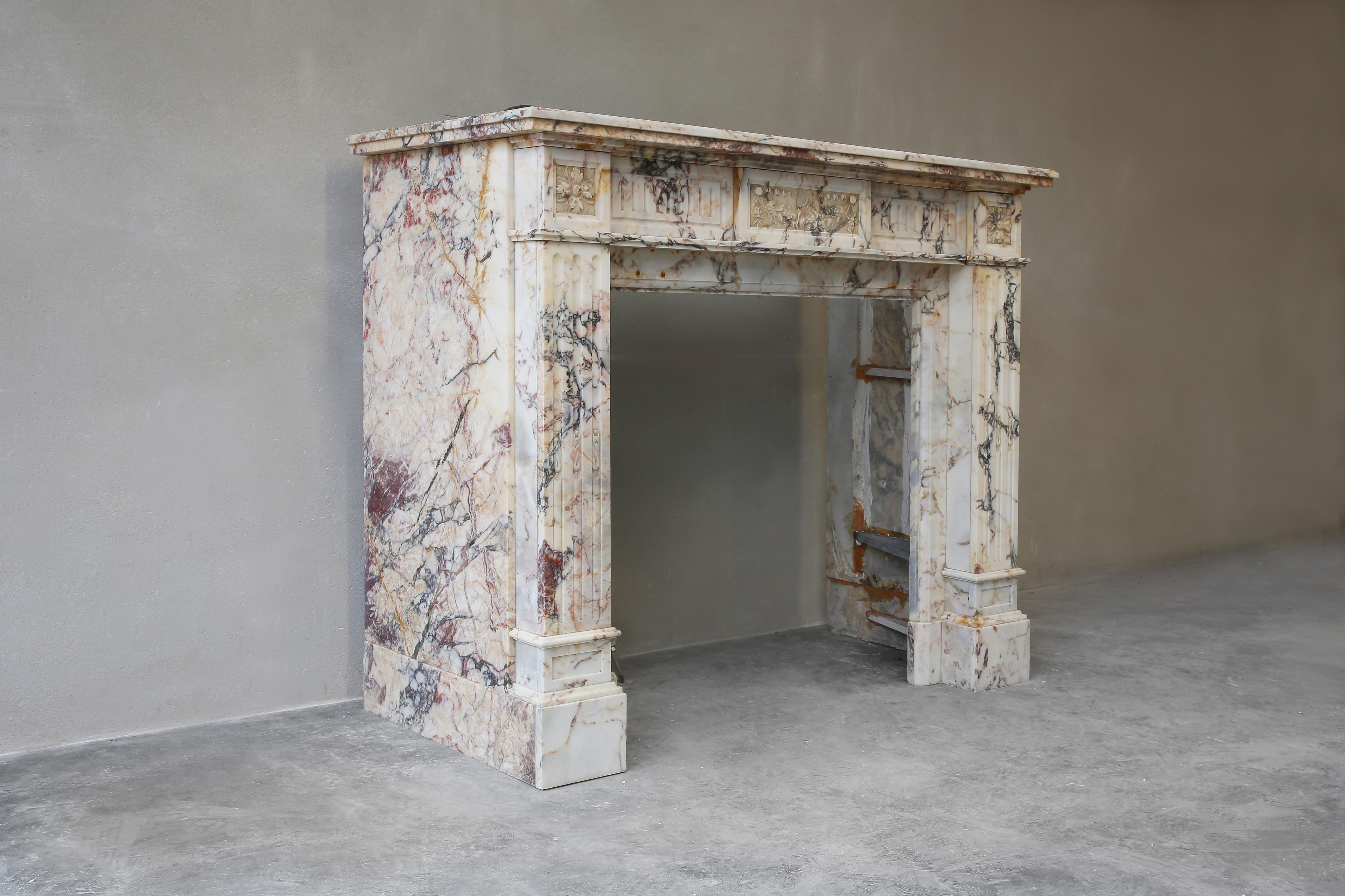 Beautiful elegant antique fireplace made of Breche marble. This fireplace dates from the 19th century and is in the style of Louis XVI. The warm color scheme in combination with the sleek shapes make this fireplace a valuable mantle within our