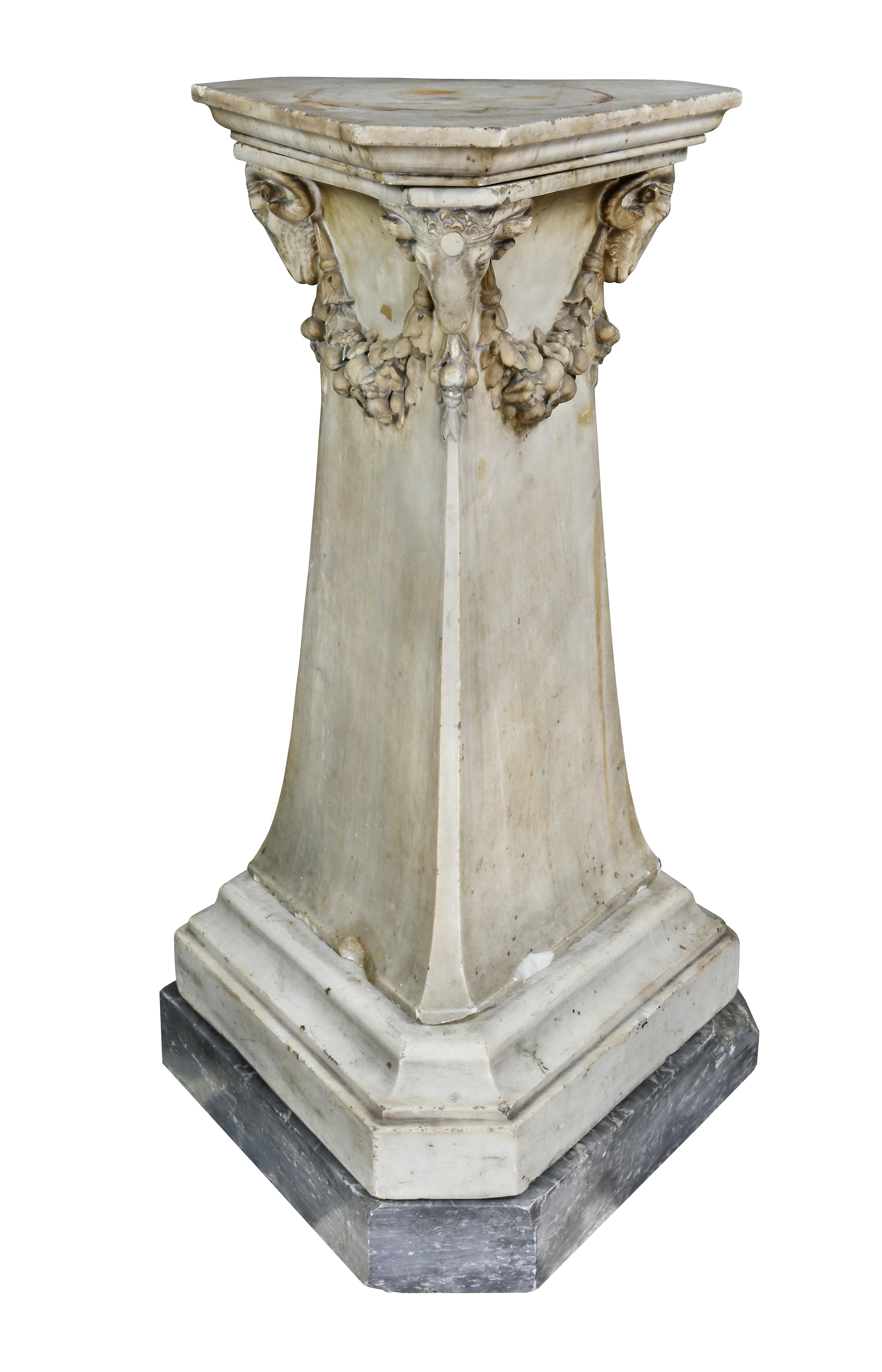 Triangular form with three carved rams heads and festoon swags, flared base and gray marble plinth. Sold Christie's East, 1983. Ex collection William Hodgins, Boston.