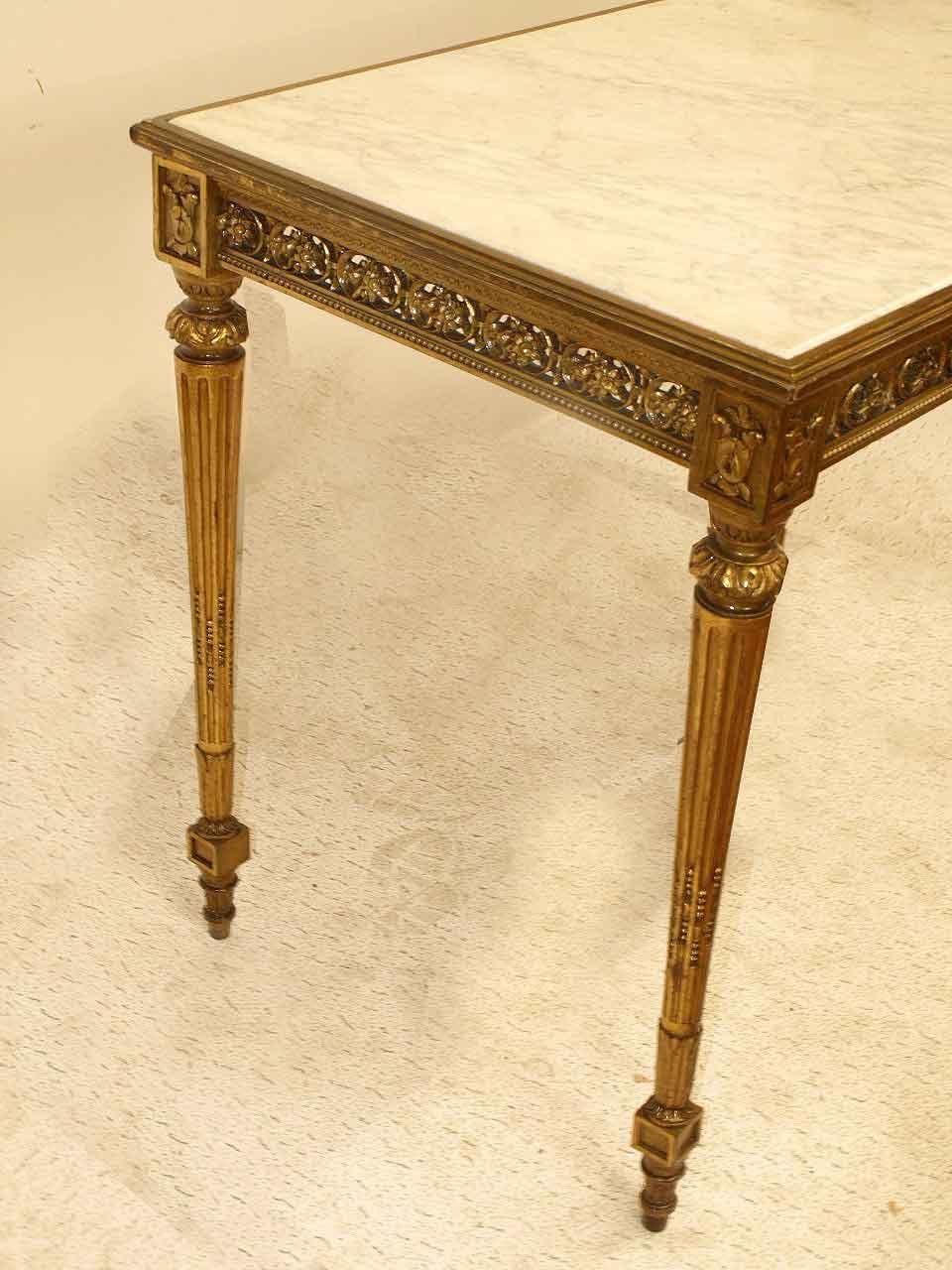 French Louis XVI marble top center table, the top with beautiful veining and beveled edge set inside a simple edge molding. This four sided gilt table has a intricately carved and reticulated frieze, nicely tapered, carved and reeded legs featuring