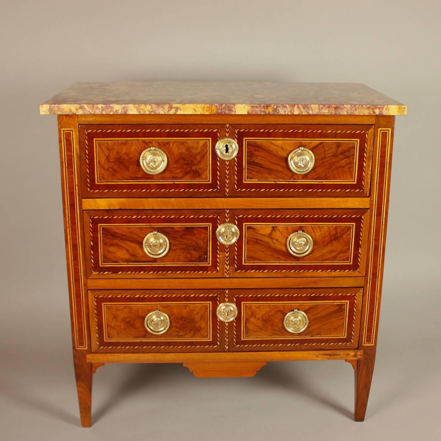 An elegant small Louis XVI marquetry commode or chest of drawer, stamped by Jean Demoulin (1715-1798). With three drawers, each drawer with two walnut panels and inlay banding simulating a twisted rope, the sides similarly veneered. The circular