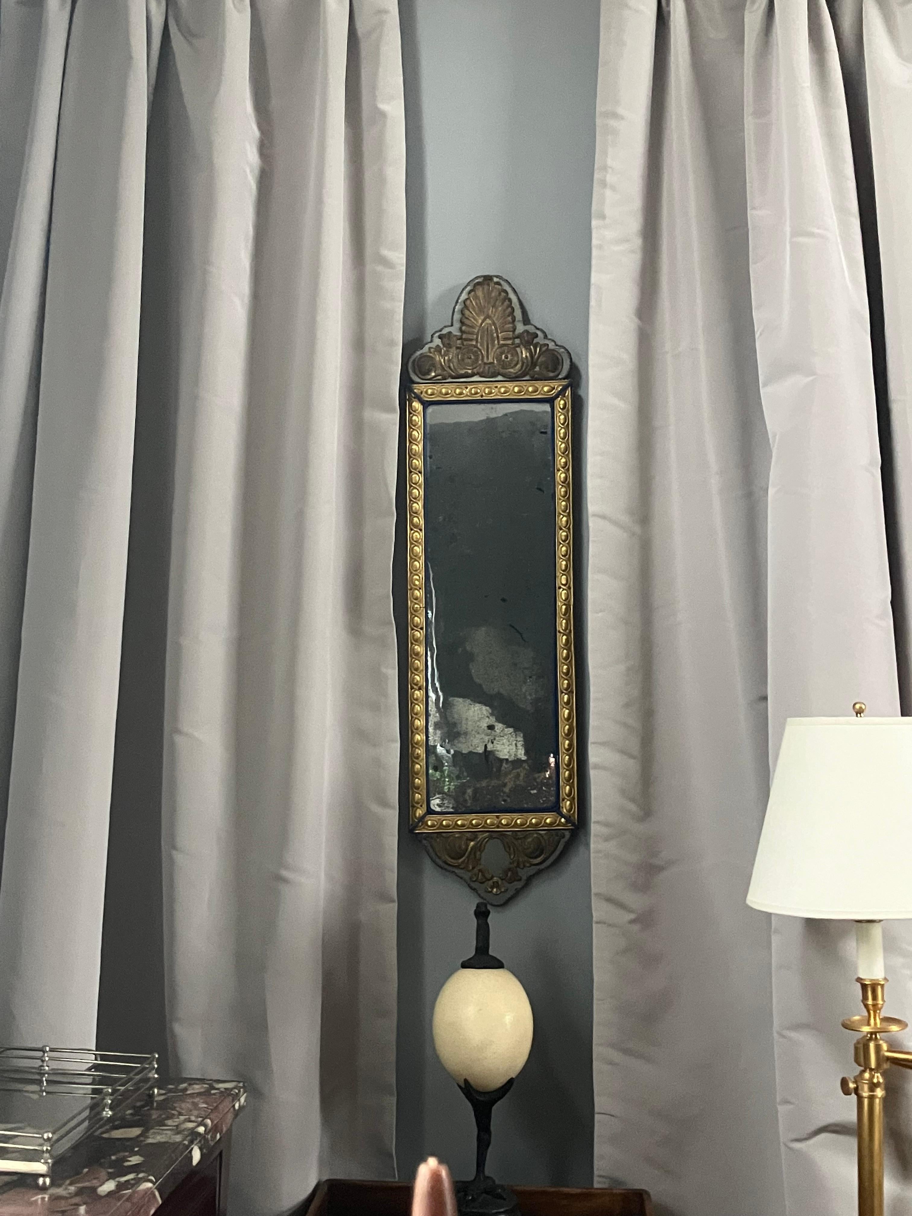 Louis XVI Mirror. Italian gilt metal long rectangular egg guilloché repousse trim framing original mercury glass mirror, with neoclassical anthemion brass repoussé top and bottom elements on pale grey blue silk backing, with grey and blue silk