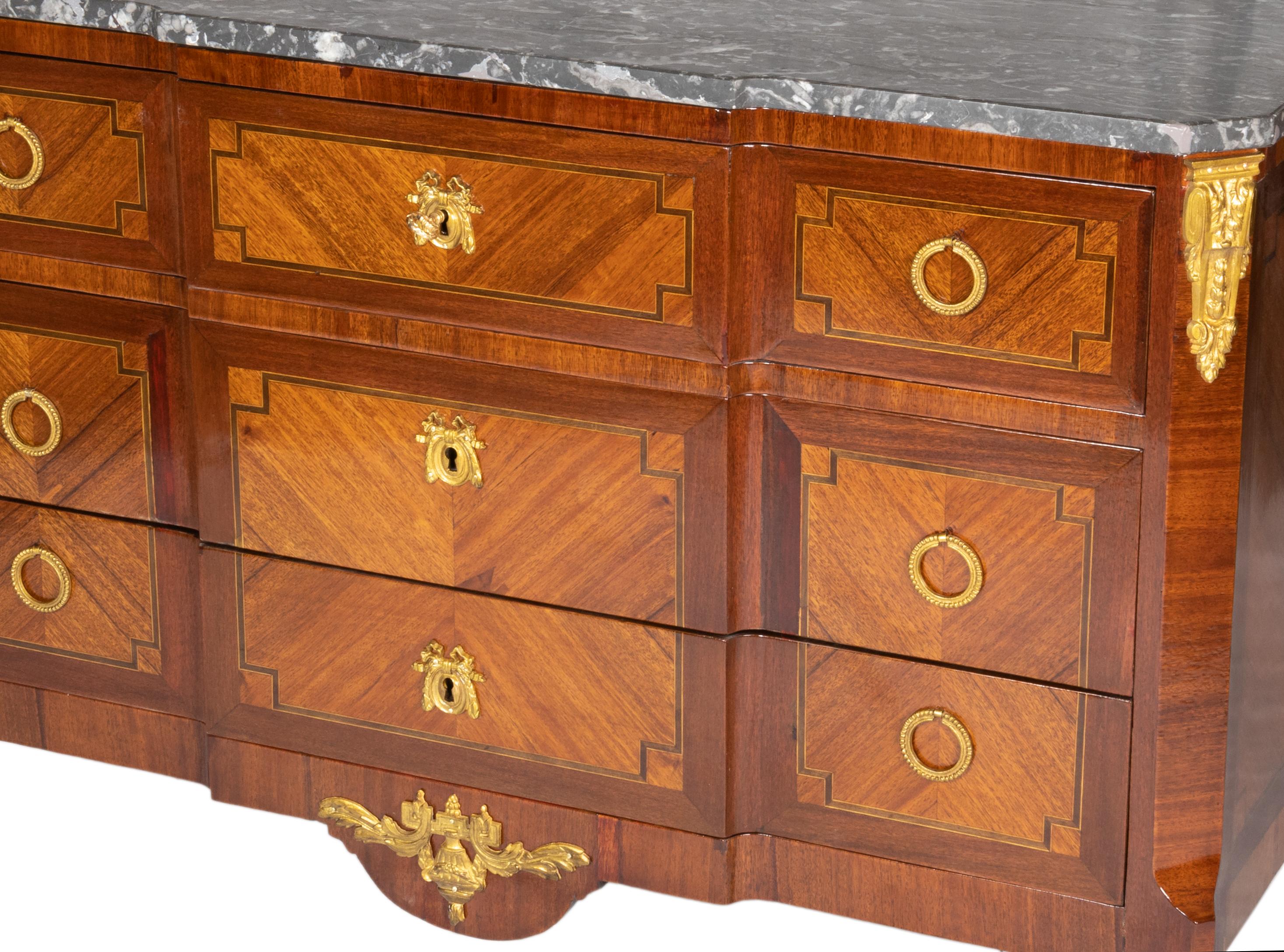 Un piano in marmo di forma franca con piedi affusolati, scarpe in ottone cesellato, maniglie e fregi intricatamente cesellati in bronzo. I fianchi laterali presentano bordi intarsiati in parquet esotico con cornice a quattro foglie, mentre il piano