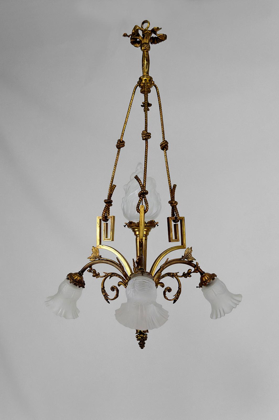 Superbe lustre de style néoclassique / Louis XVI.
France, Circa 1900.
4 lampes.
En bronze doré avec des motifs floraux, des raisins, des torches, des nœuds de corde.
Belle verrerie : flamme sur le luminaire central, drapé de tulipes.

Bon