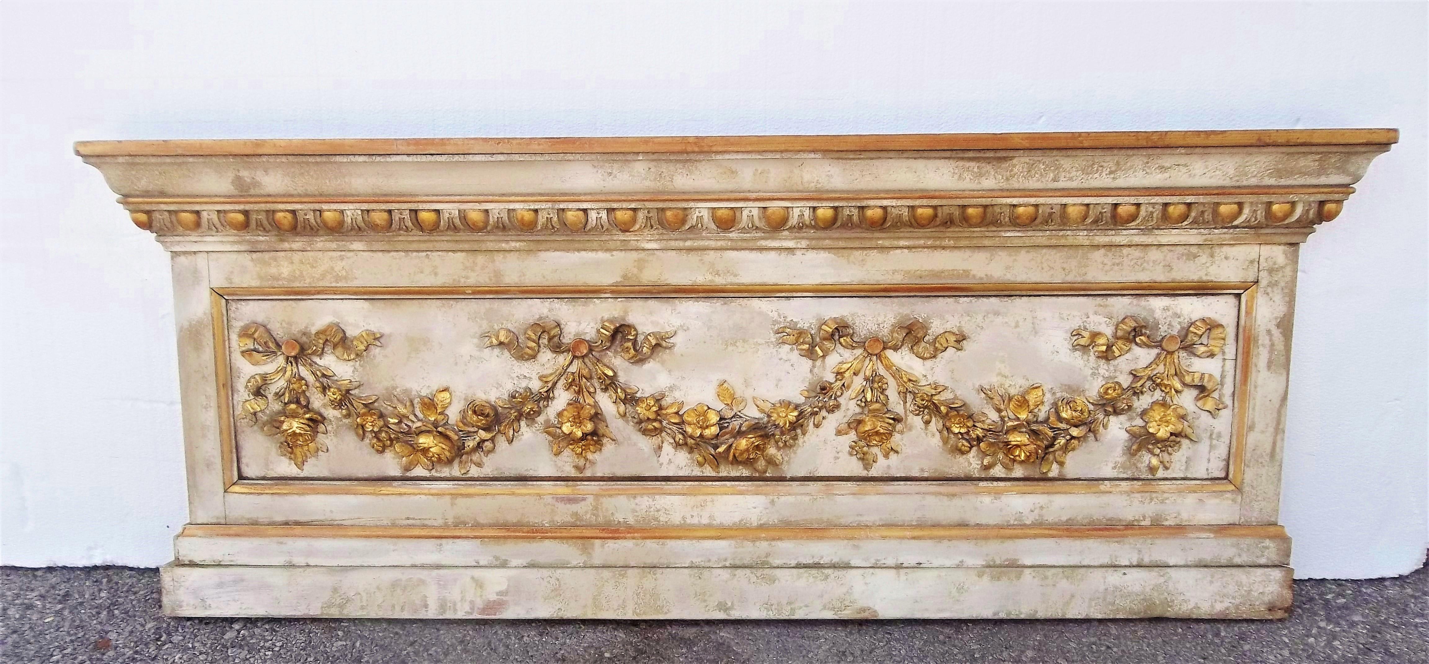 With floral festoons hung in garland form. Wear to paint and gilding as shown in photos. Centre panel (with the garlands) has a bow, more obvious from the back. Probably from a ballroom (or at least a formal room)

Gilding worn in places with red