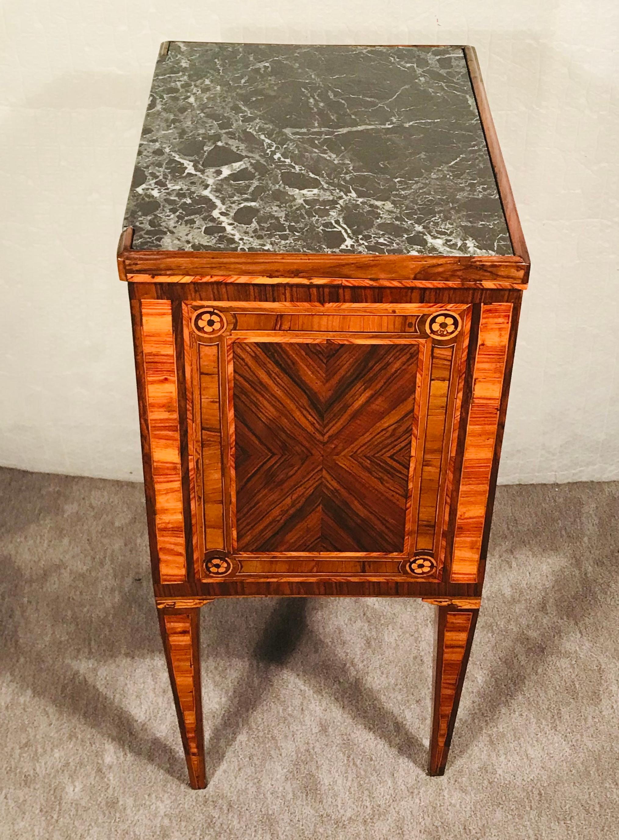 Discover the timeless charm of our Antique French Louis XVI Nightstand, meticulously crafted in 1780. This rare and beautiful piece stands gracefully on four tapering legs, showcasing exceptional marquetry and walnut veneer craftsmanship.

The