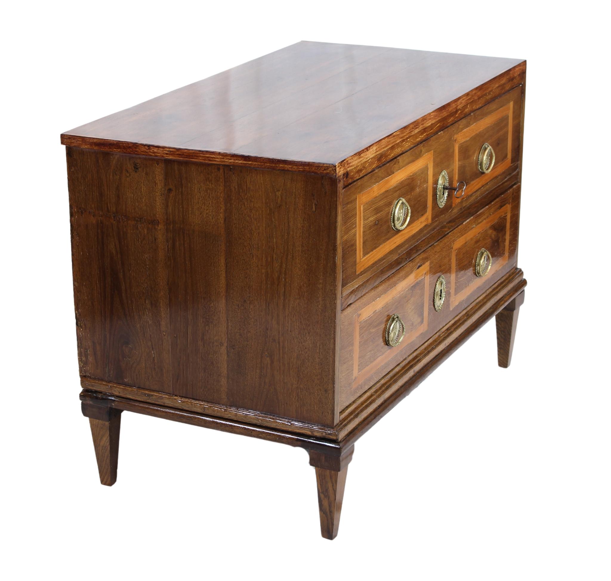 Discover a stunning piece of history with this Louis XVI chest of drawers from 1780. Crafted from solid oak, this exquisite commode showcases the timeless elegance of the period. Its two spacious drawers feature intricate cherrywood band inlays,
