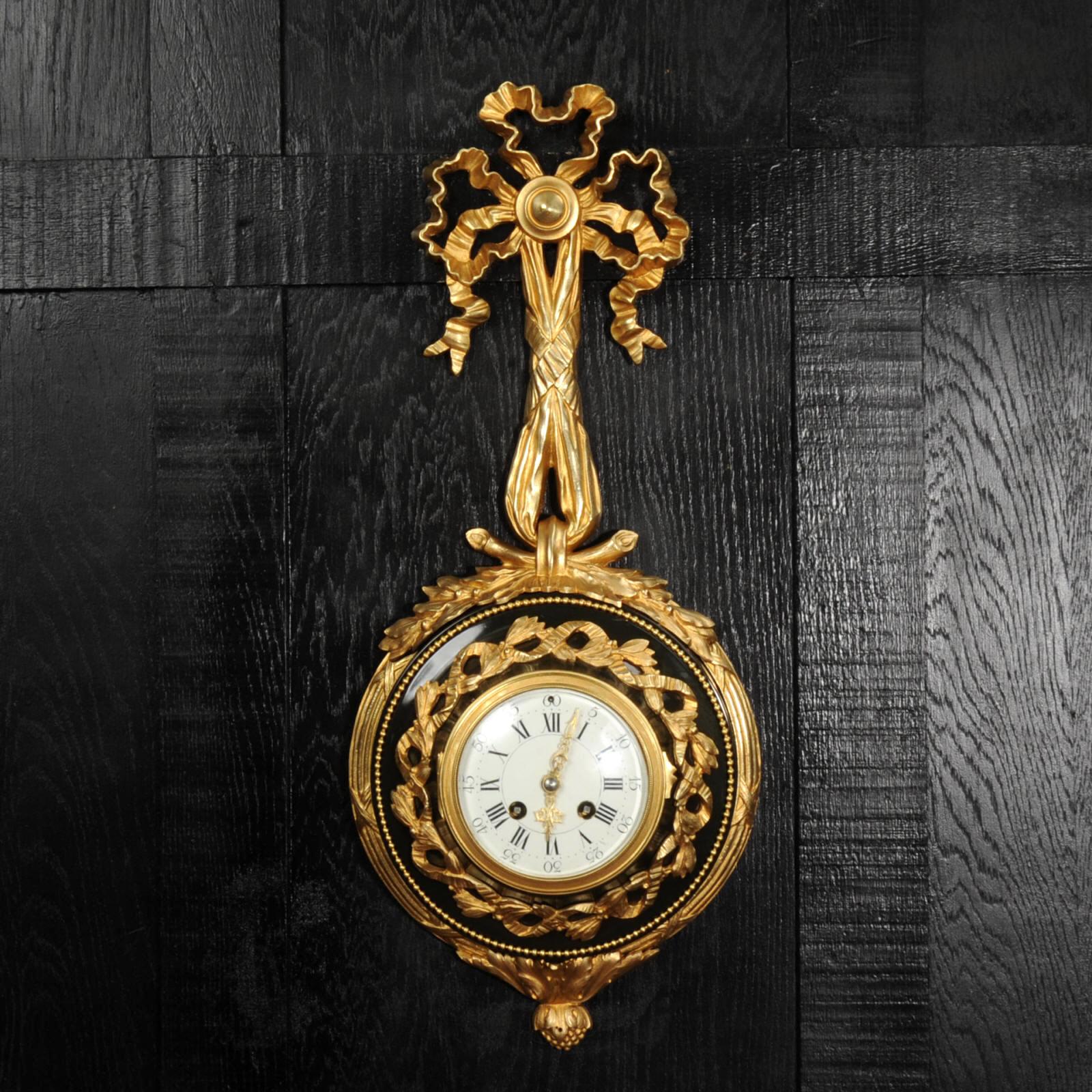 A Beautiful Louis XVI-Style Cartel Wall Clock by Samuel Marti This elegant French cartel wall clock, in the refined style of Louis XVI, is a fine work by the esteemed maker Samuel Marti. The clock features a round bronze case housing the movement,