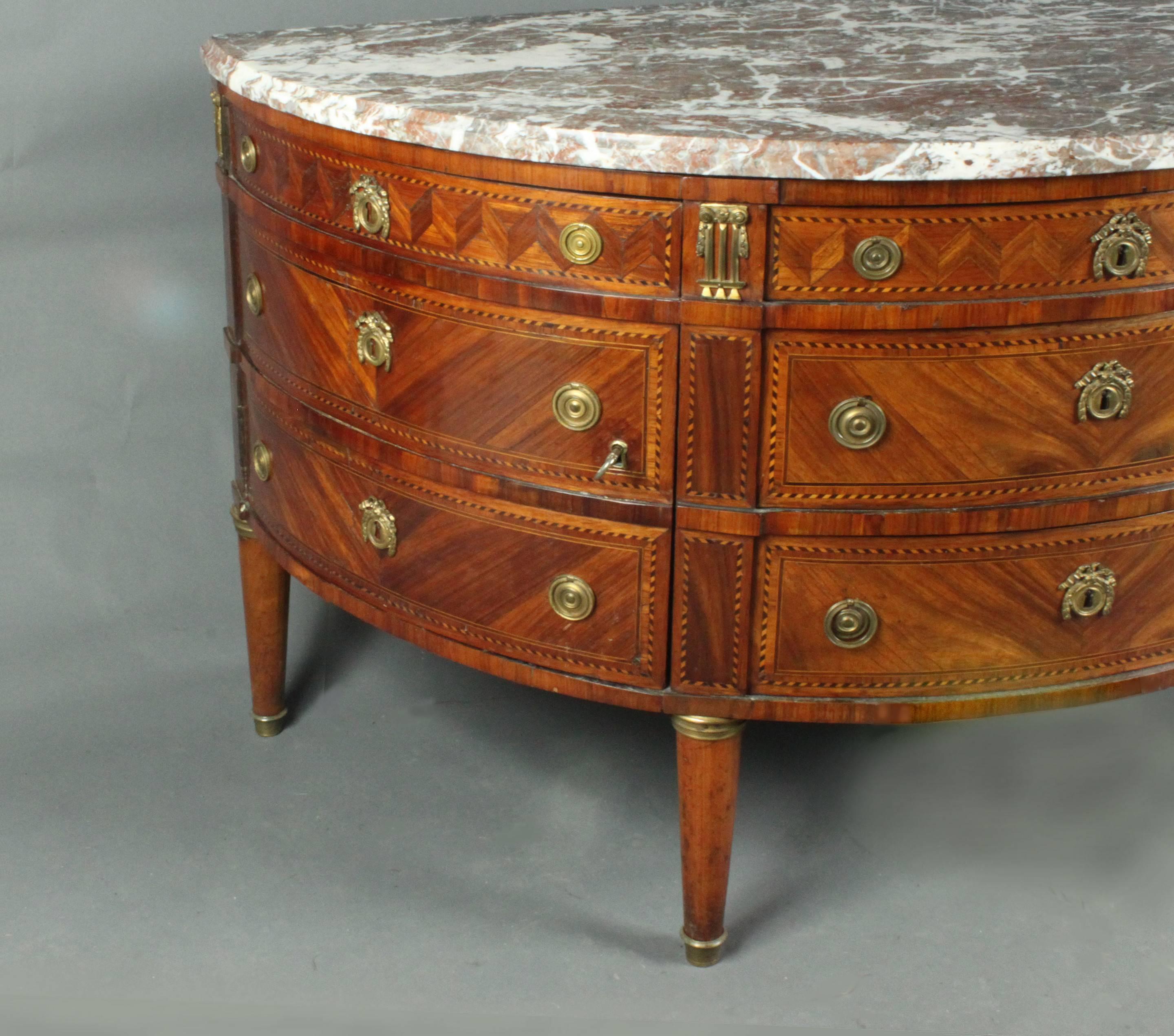 A fine Louis XVI ormolu-mounted demilune kingwood commode: The marble top over three frieze drawers with two further drawers in the centre flanked by a pair of cupboards each enclosing a shelf, on turned tapering legs.

Please note, this piece