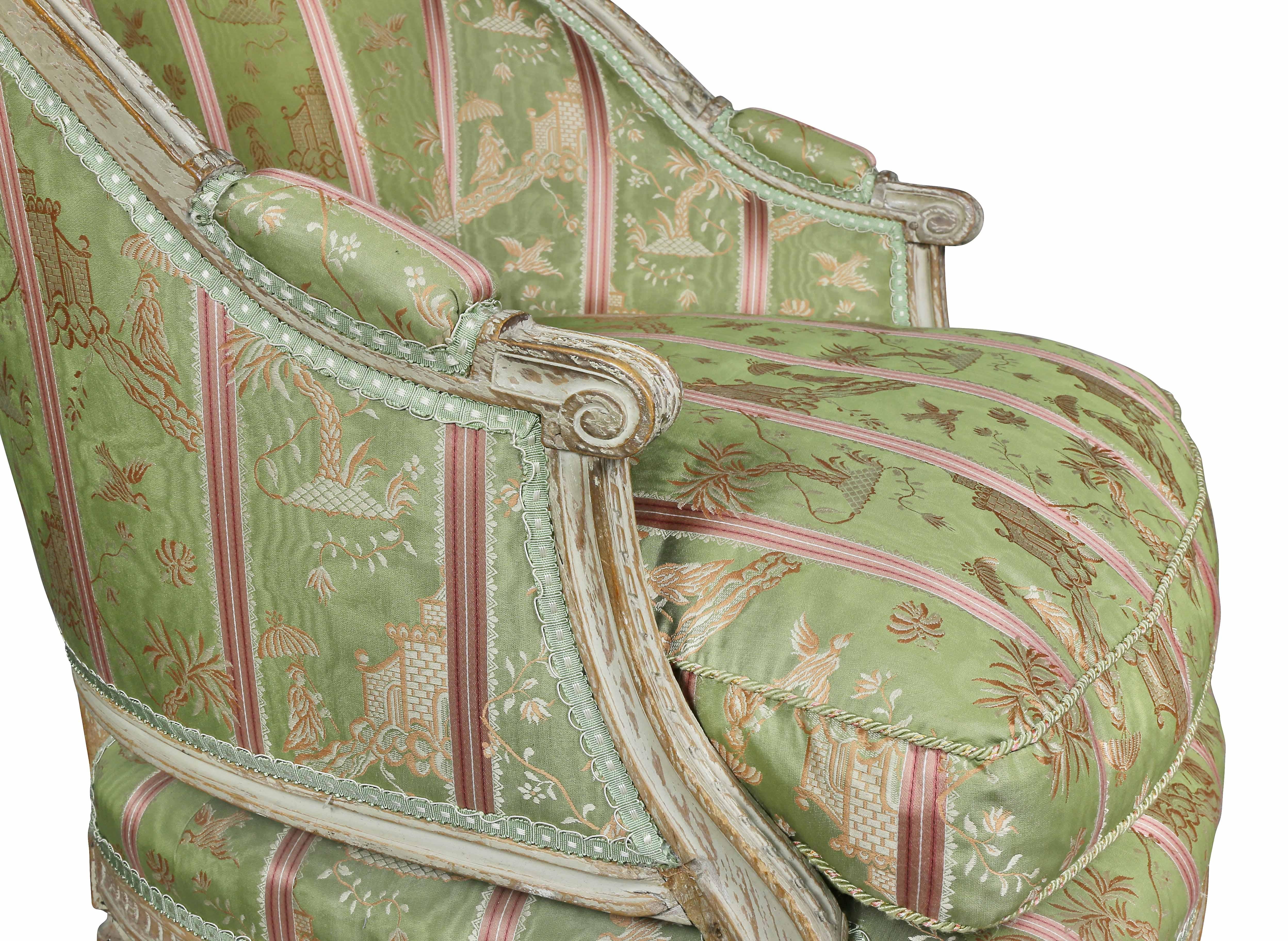 Arched carved back and seat with loose cushion upholstered in a striped green silk fabric, circular tapered fluted legs.