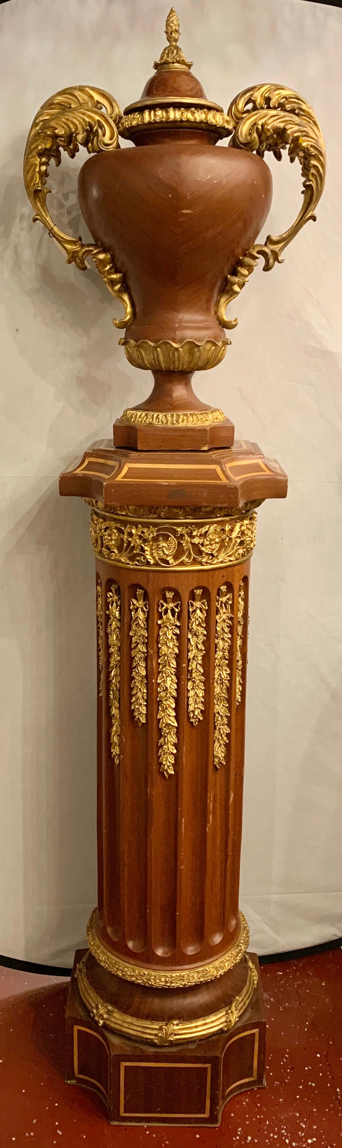 Pair of French circa 1950 urns and cover on pedestals. A pair of magnificent wood pedestals of gilt and paint design supporting a large pair of wooden lidded urns. If an impressive entry is what is needed these are exactly what is called for.