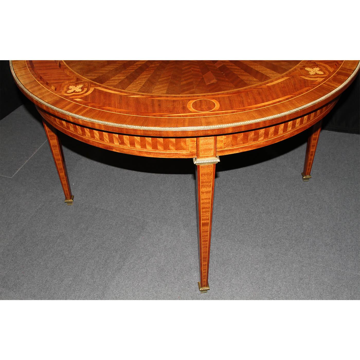 A fine Louis XVI style parquetry inlaid round center table with an inlaid and rayed top of various exotic woods, with marquetry inlaid crossbandings, with bronze ormolu trim, capitals with a parquetry inlaid apron and raised on square tapered legs.