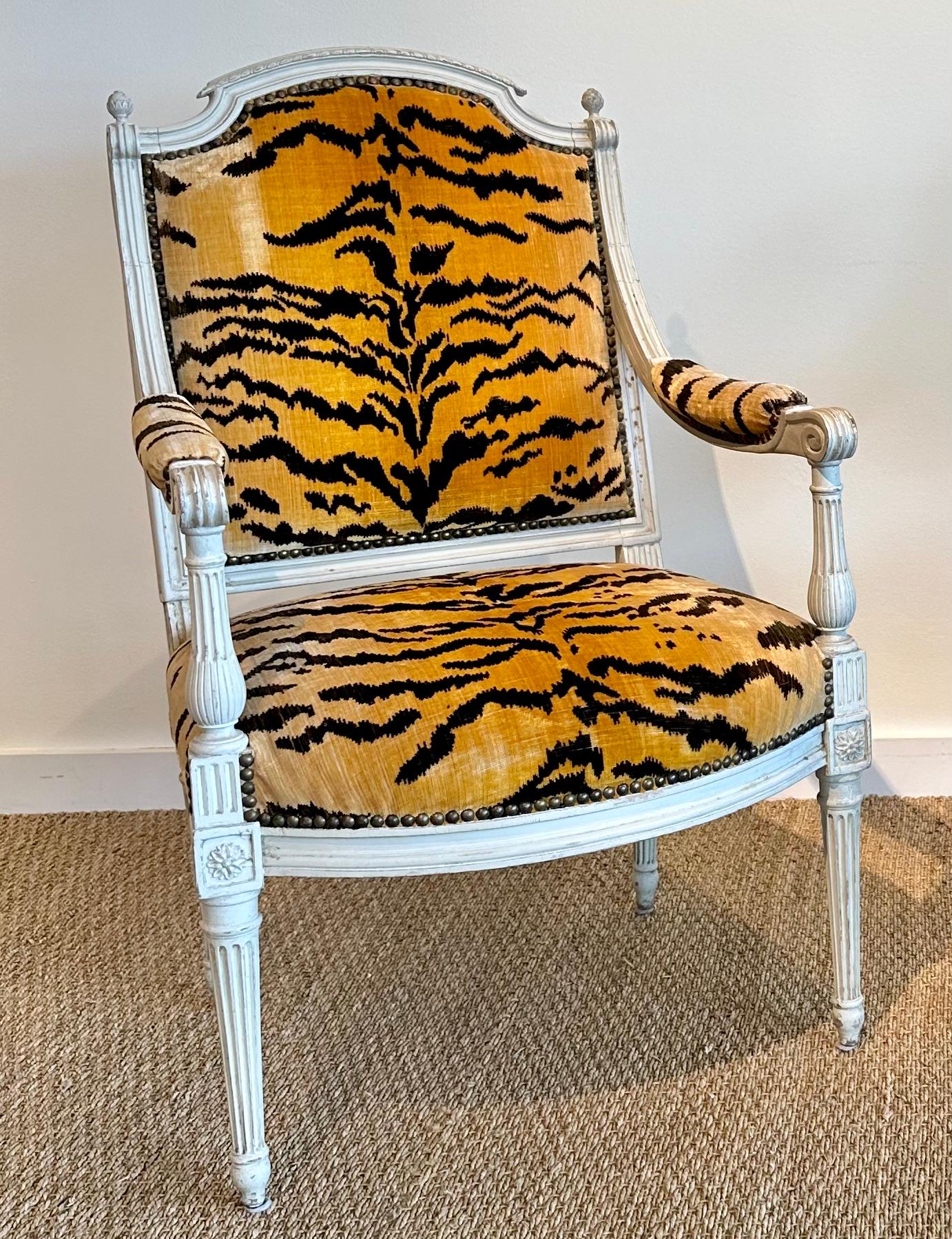An excellent pair of Louis XVI open armchairs painted off white upholstered in a silk velvet with a tiger pattern; each is signed S.BRIZARD (Sulpice Brizard became a master in 1762). The arched top back rail is carved with a gadrooning and is