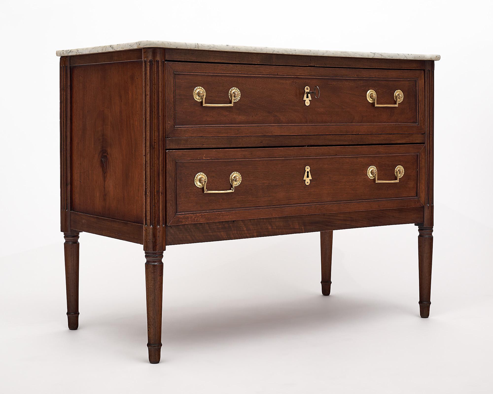 Chest of drawers, French, from the Louis XVI period. This chest is from the Rhone valley and made of solid walnut with a hand rubbed bees wax finish. Two dovetailed drawers each have brass hardware. The “commode” is topped with its original Carrara