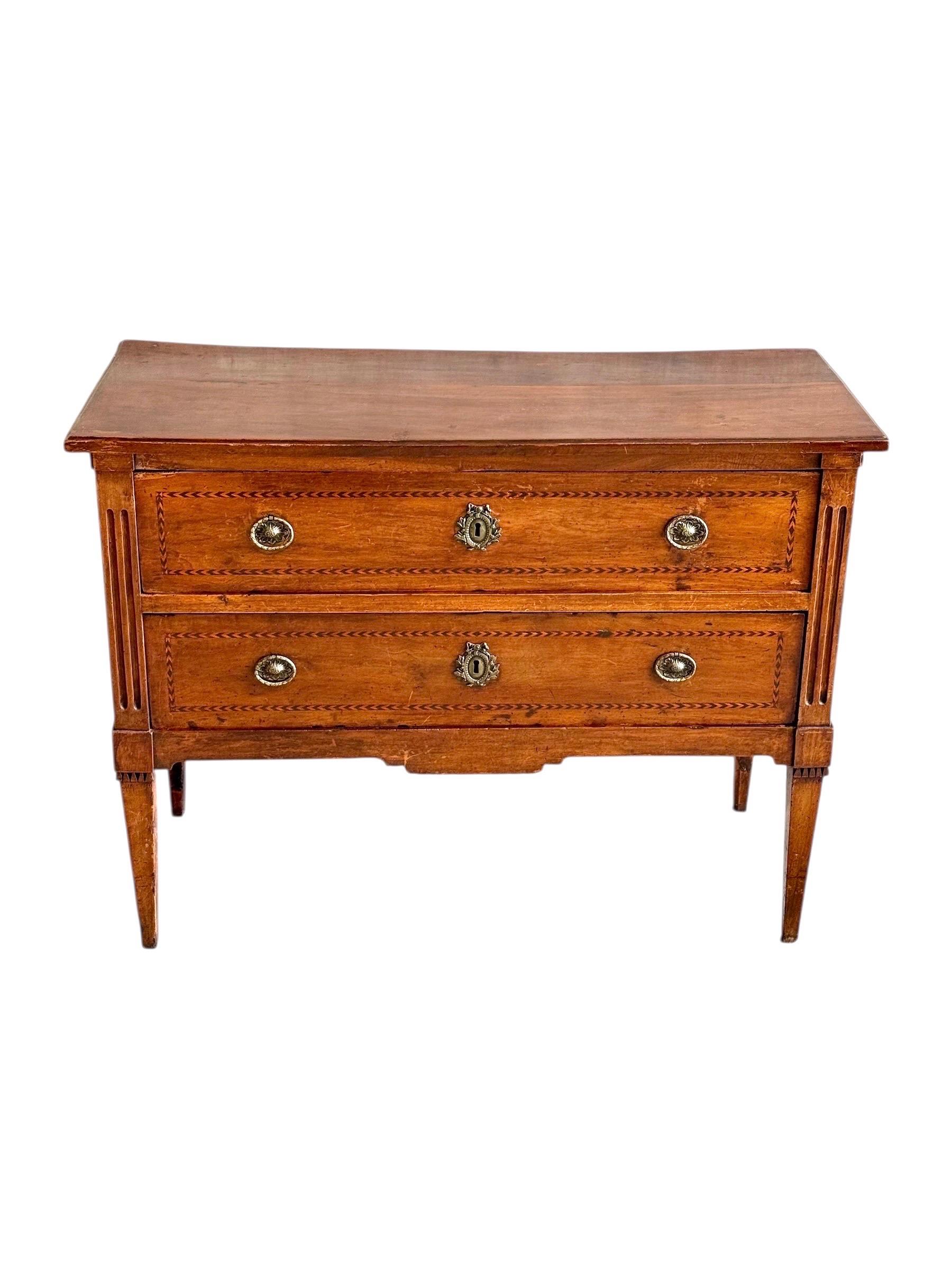 Elegant French Louis XVI period commode crafted in cherrywood with fine geometric marquetry inlay, dating from the late 18th century, circa 1780. This refined piece features two spacious drawers with intricate chevron inlaid borders and original