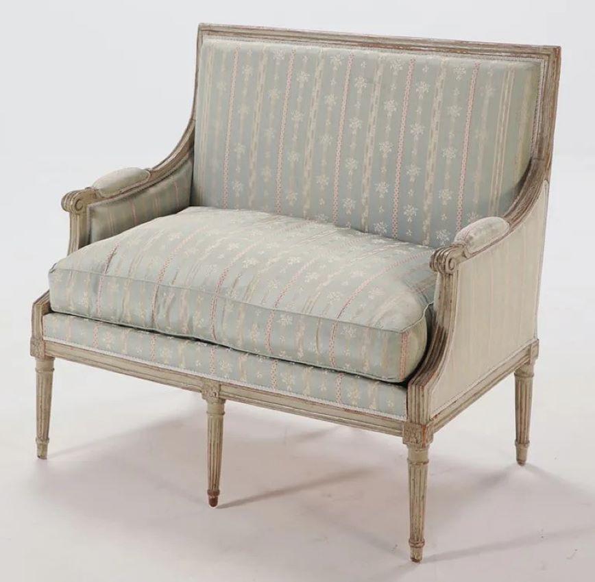 Marquesa (bergere ancho) de época Luis XVI del siglo XVIII, en acabado original pintado de color crema, con un sencillo respaldo cuadrado tapizado, brazos y laterales acolchados, con asiento de cojín relleno de plumón, todo ello sobre patas