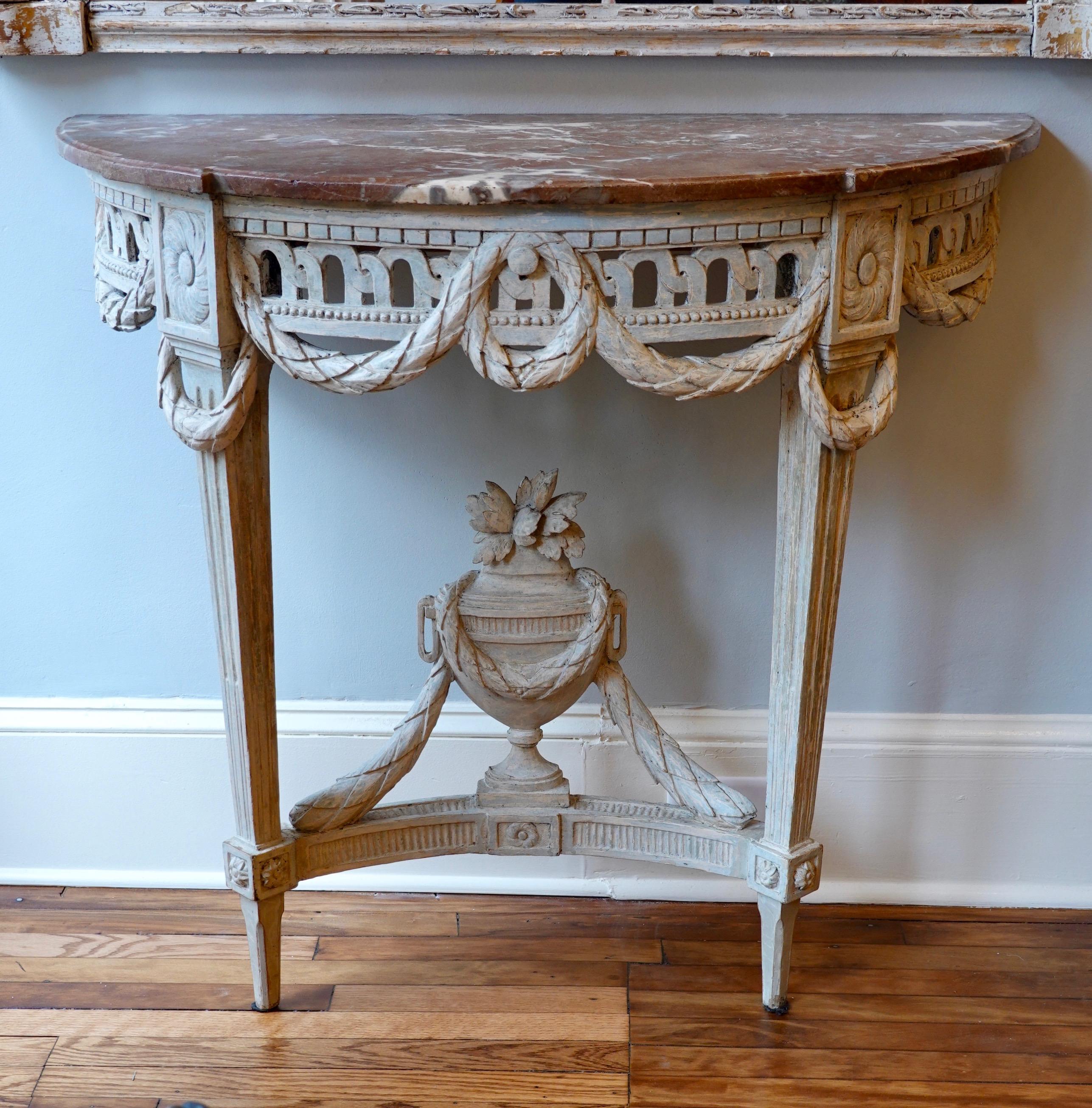Lovely Louis XVI period white-painted console table (18th century) with pierced apron ornamented with swags, rosettes on joints, and large urn with flowers and swags on stretcher with other neoclassical details (circa 1780). Very pretty, variegated