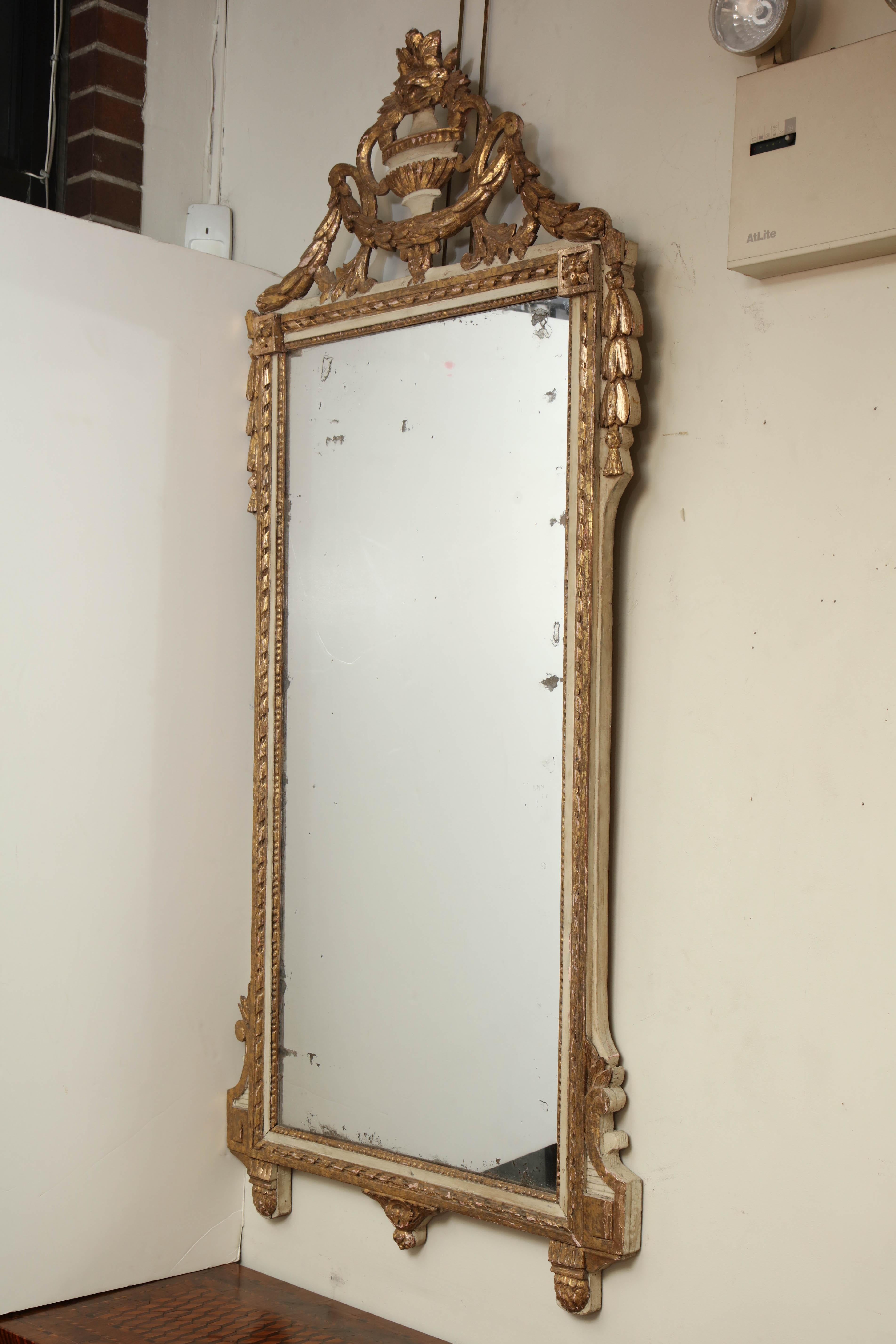 A fine French Louis XVI painted and gilded mirror with a carved floral urn, bellflowers and ribbon frame.