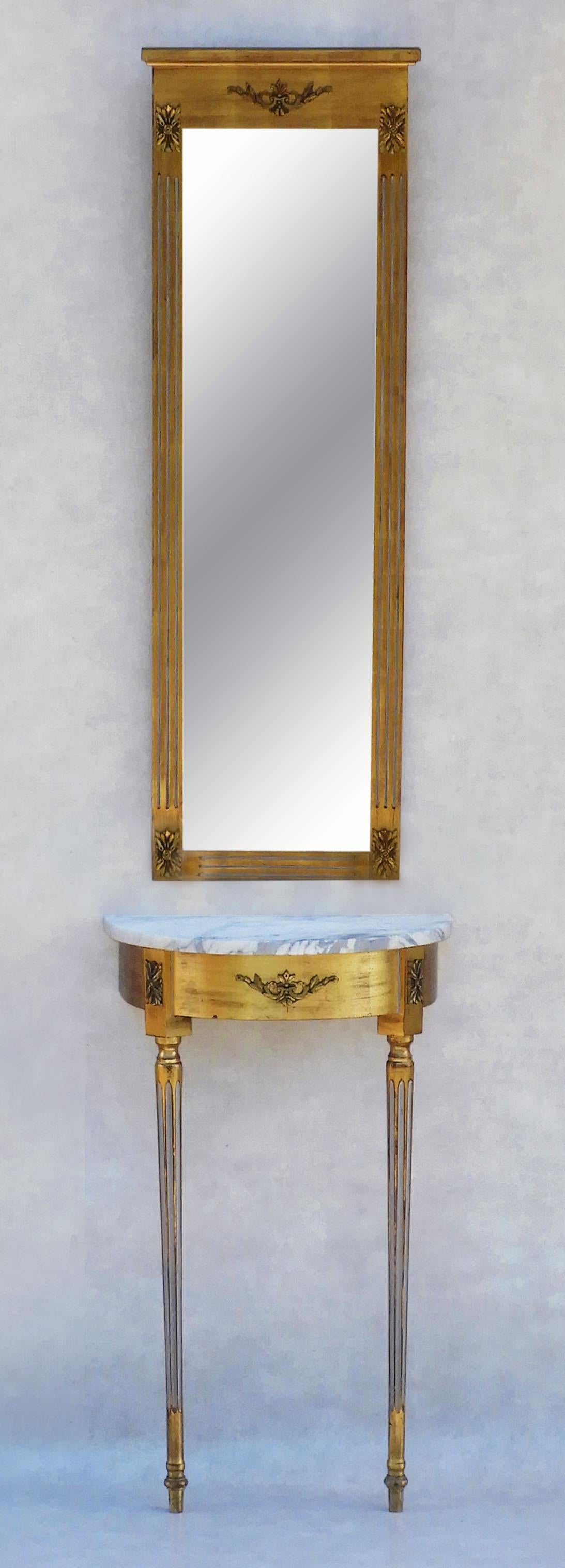 A gorgeous Louis XVI Revival giltwood and marble console table and bevelled mirror, c1950s France. 
Beautiful giltwood gesso and wall-mounted table, topped in white veined marble and a tall and slender bevelled mirror. 
Stylish and simple