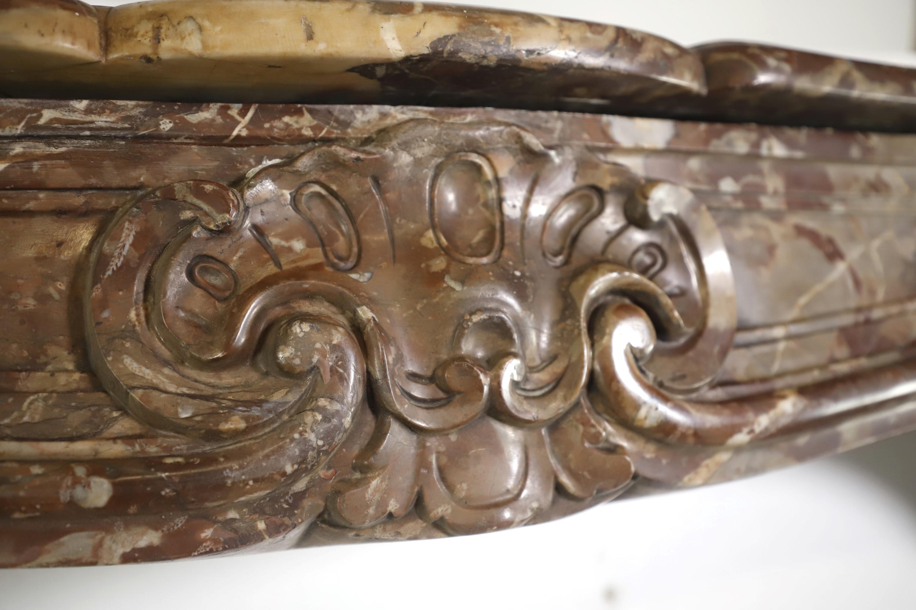 Retrieved from a 1926 residence at 950 5th Ave and East 76th St in Manhattan, NYC. This mantel was hand carved from brown rouge royal marble and features light grey and white accents. The serpentine front apron has an arched and scrolled center