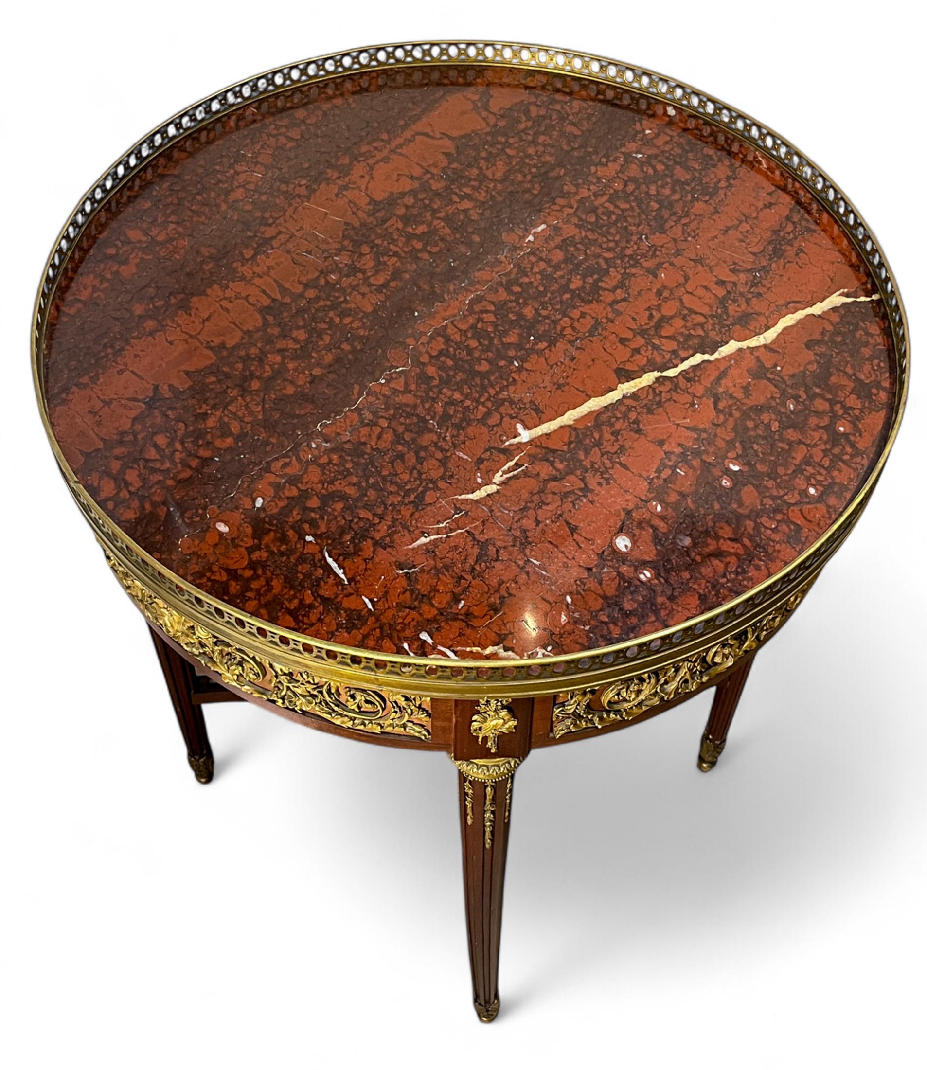 Table d'appoint de style Louis XVI en acajou et marbre rouge avec un tiroir caché et un bouton d'ouverture. Elle est ornée de montures en bronze doré représentant des formes de volutes, des fruits, des rubans de soie et des oiseaux. Avec sa