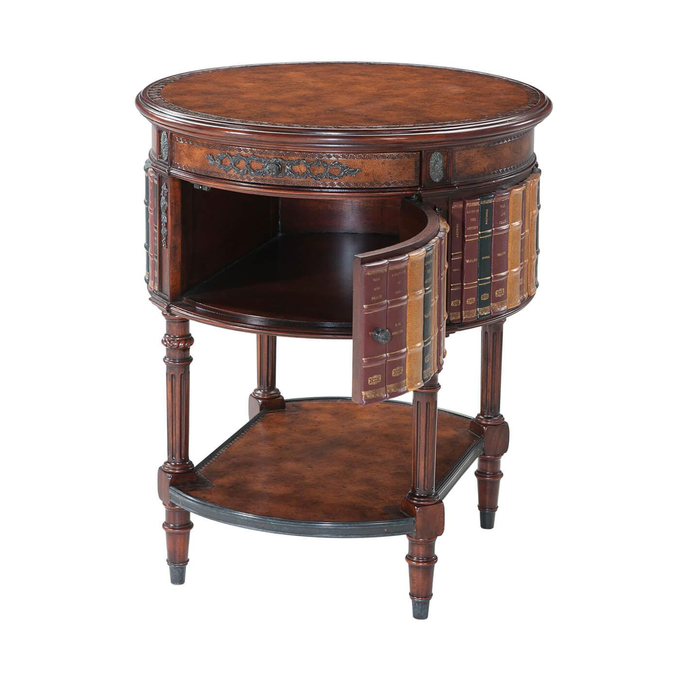 A Louis XVI style round lamp table with a faux book panel, verdigris brass mounts, aged brown leather top and under tier, drawer and cabinet, turned fluted legs. 

Dimensions: 24“ W x 24“ D x 28“ H.

 