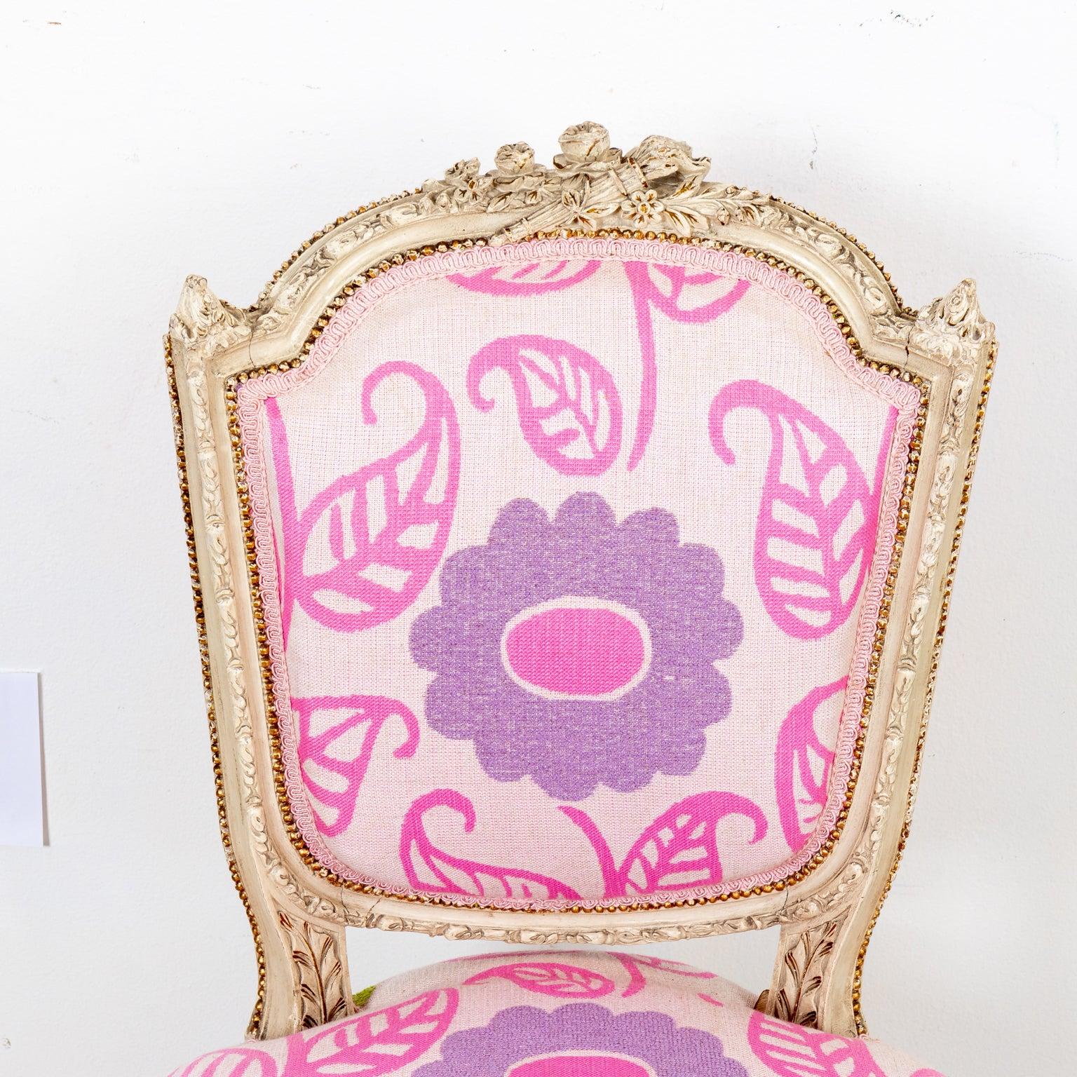 Pink and purple floral upholstered Louis XVI style side chair with painted wood frame on round, fluted turned legs. The chair is detailed with a carved flower and flaming torch motif on the seat back, flower motifs on the front of the seat rail,