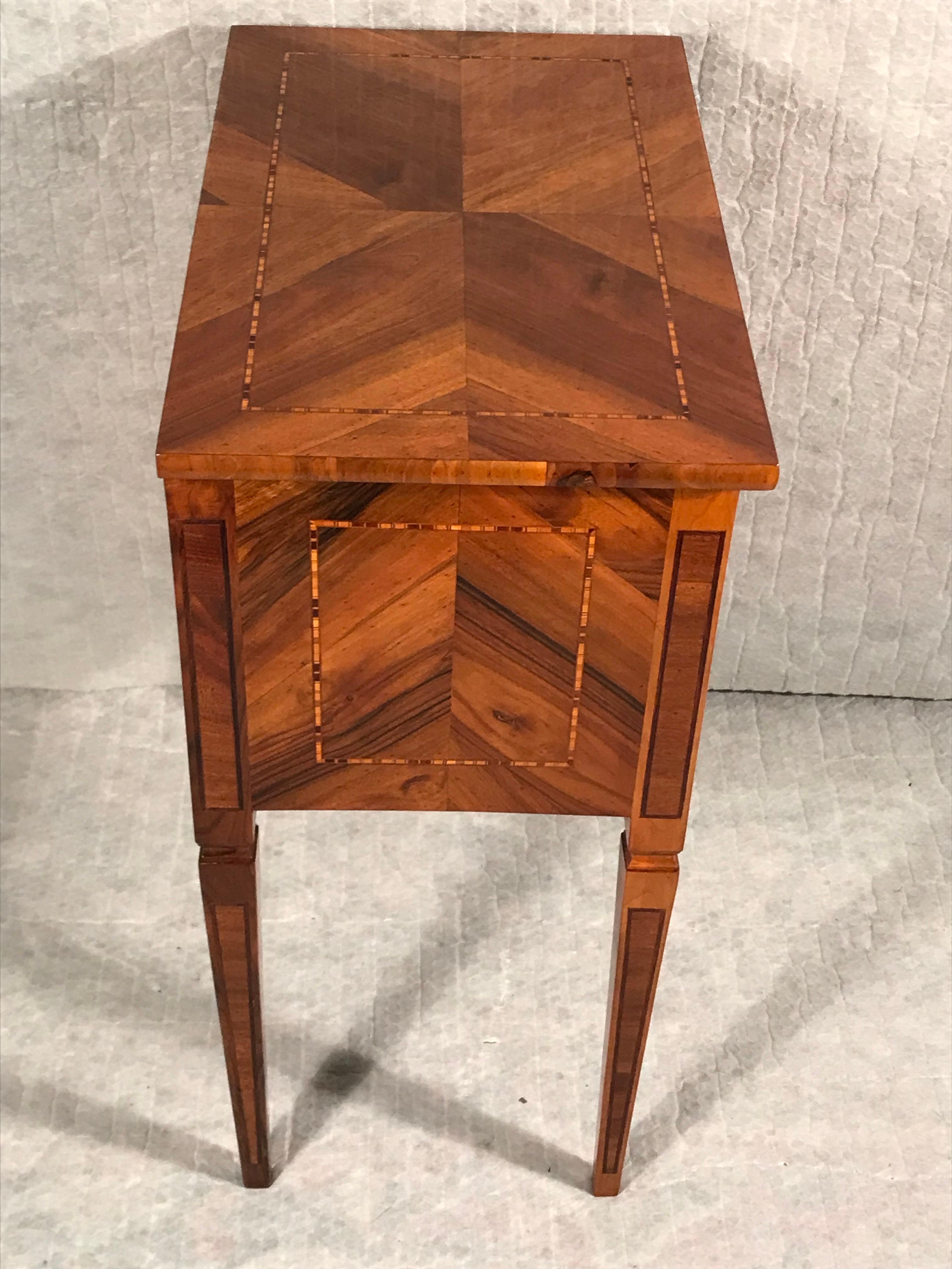 This beautiful side table from the Louis XVI Period dates back to 1780 and comes from southern Germany. The side table has two drawers. It is decorated with a pretty walnut veneer and inlaid plum and walnut band intarsia. It comes expertly