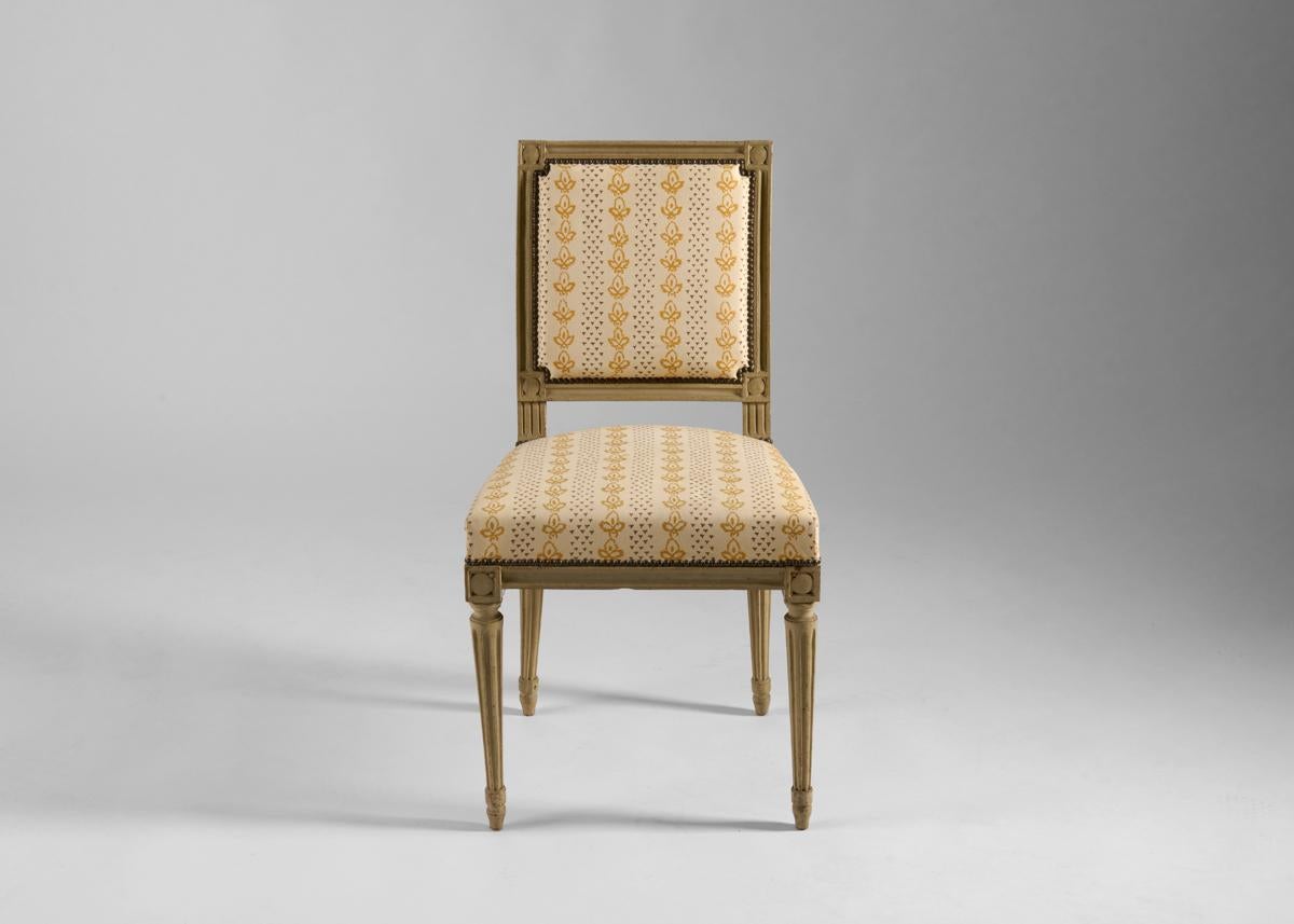 This charming Louis XVI side chair possesses a remarkable solidity for a piece of its size. Built out of hand carved, painted wood, it is appointed in elegant lines of brass detailing, which perfectly frame its upholstered