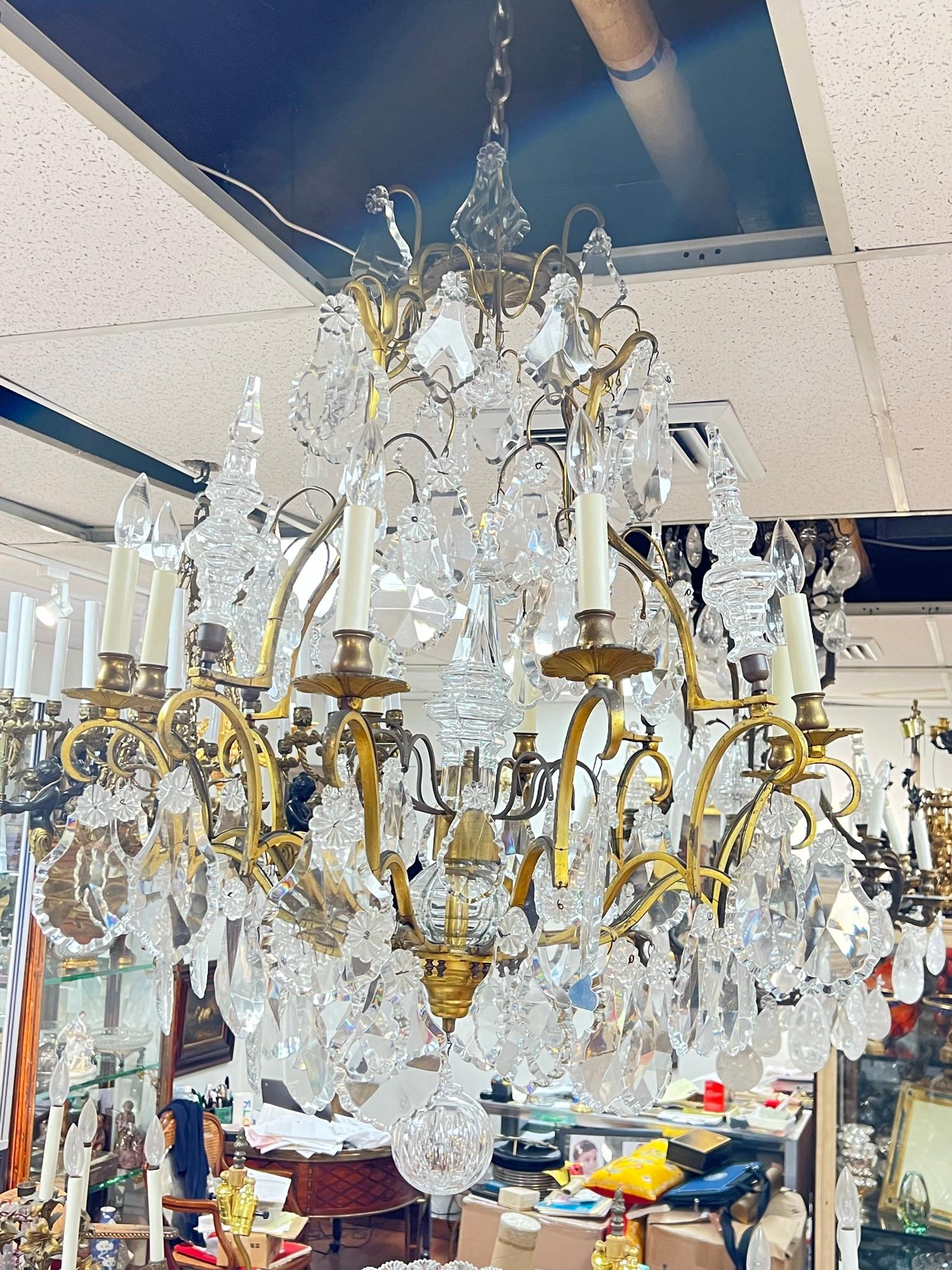 Our monumental French chandelier in the neoclassical Louis XVI style has numerous crystals including spires and cut-glass pendants, and twelve electrified candle arms with white candle covers. Stamped FRANCE at the base.