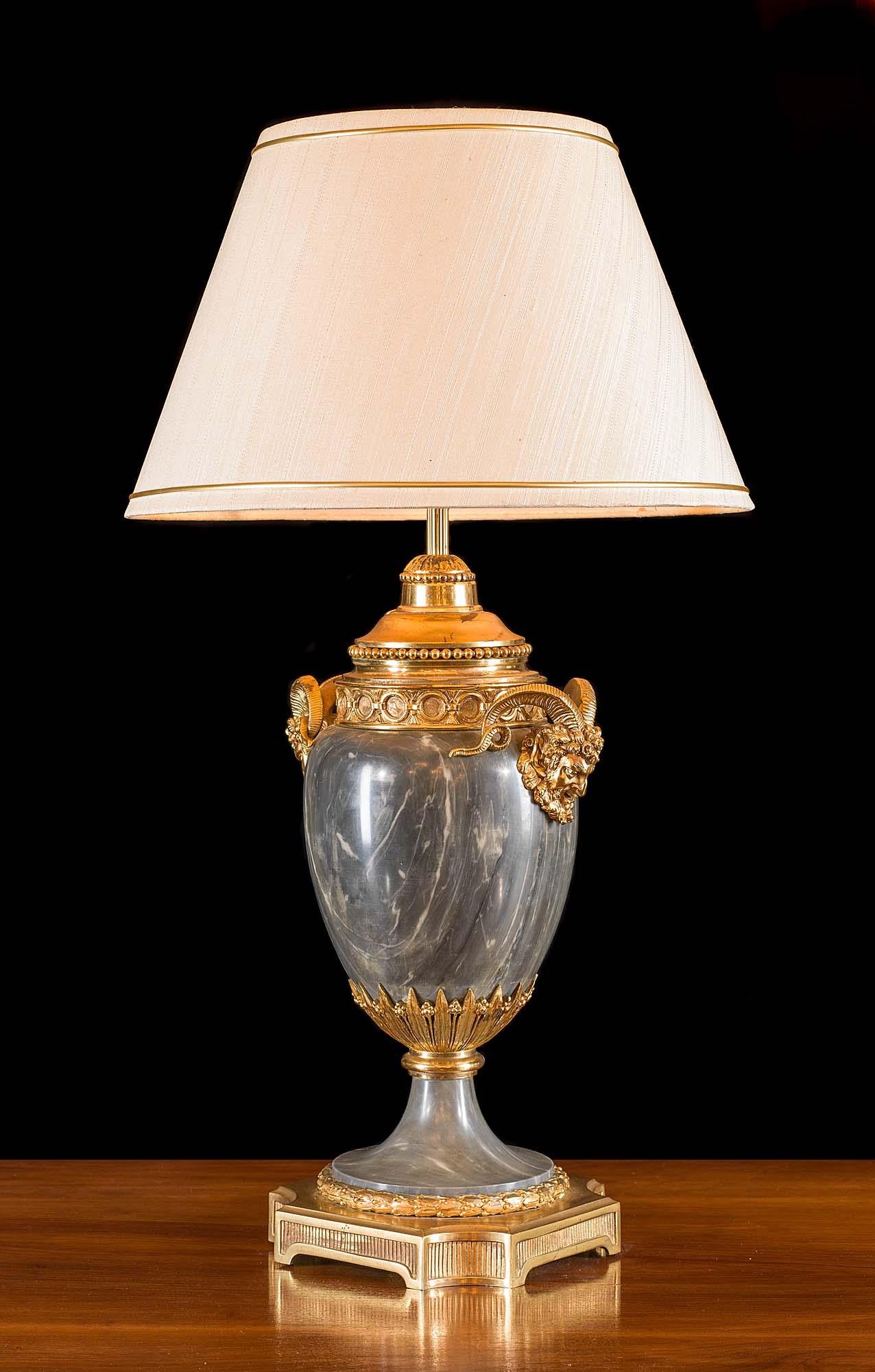 A charming, Louis XVI style, grey marble and ormolu table lamp, raised on a pedestal base and with a pair of bold ormolu satyr masks, with large sweeping horns, mounted on the shoulders, French, circa 1880.

Dimensions include shade.
    