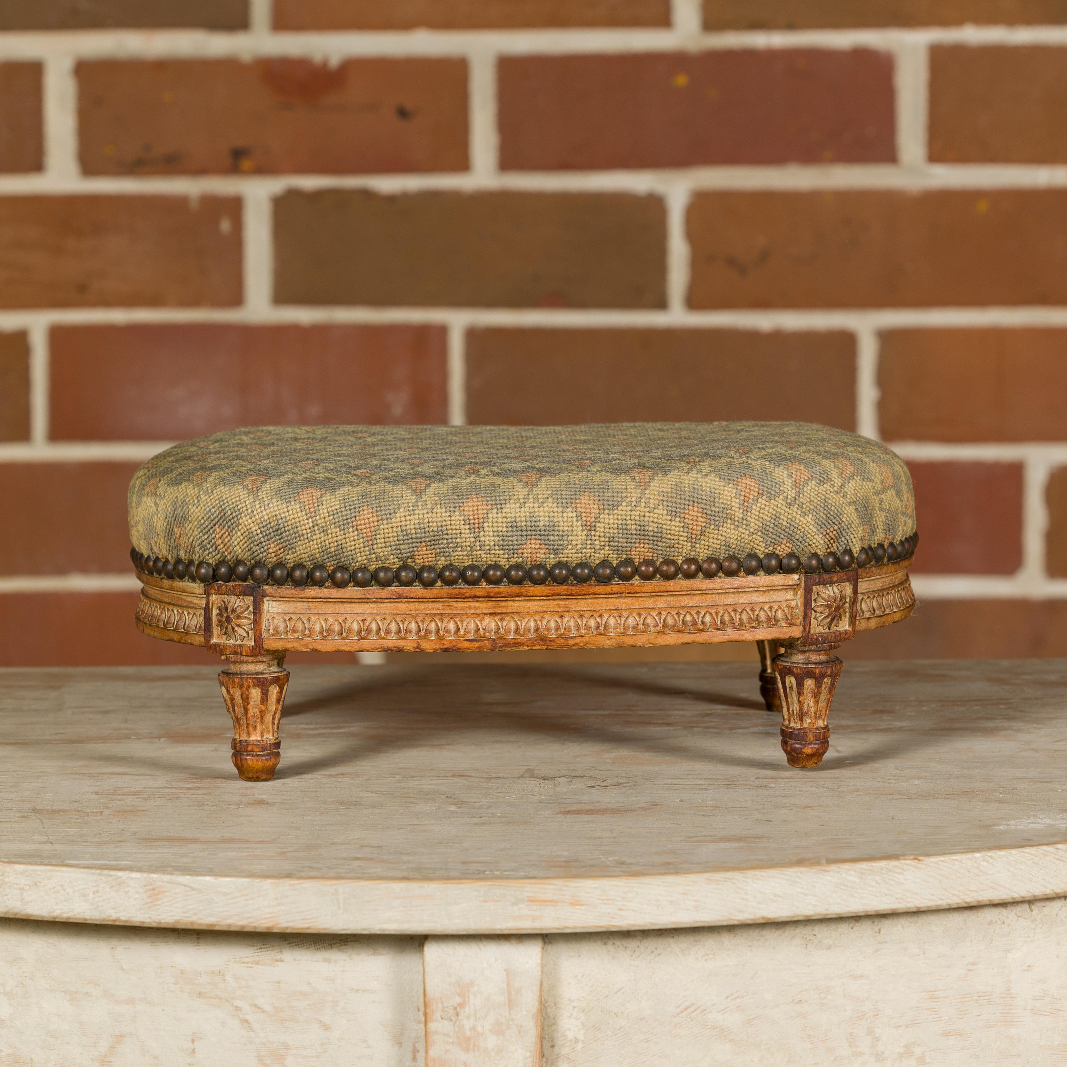 A French Louis XVI style wooden footstool from the late 19th century stamped Alexandre Pihouée with carved base, tapered fluted legs and needlepoint upholstery. Indulge in the refined elegance of the late 19th-century French Louis XVI style with