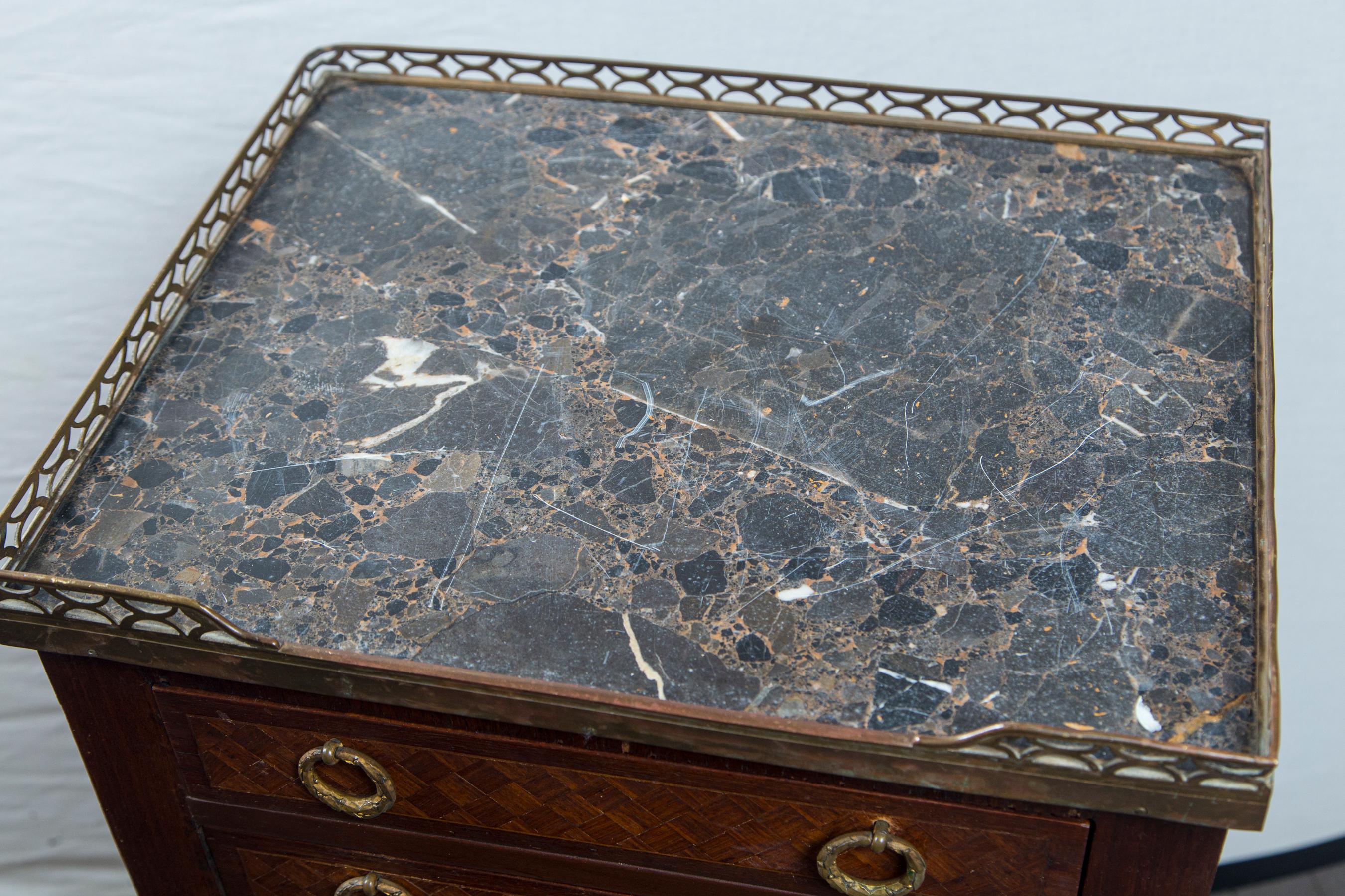 The entire body covered with parquetry geometric design. Pulls are in the form of wreaths and appear to be original. Brass gallery, open at the front, is at 31. 25 inches. The marble of dark and light brown with veining of white, the top and toe