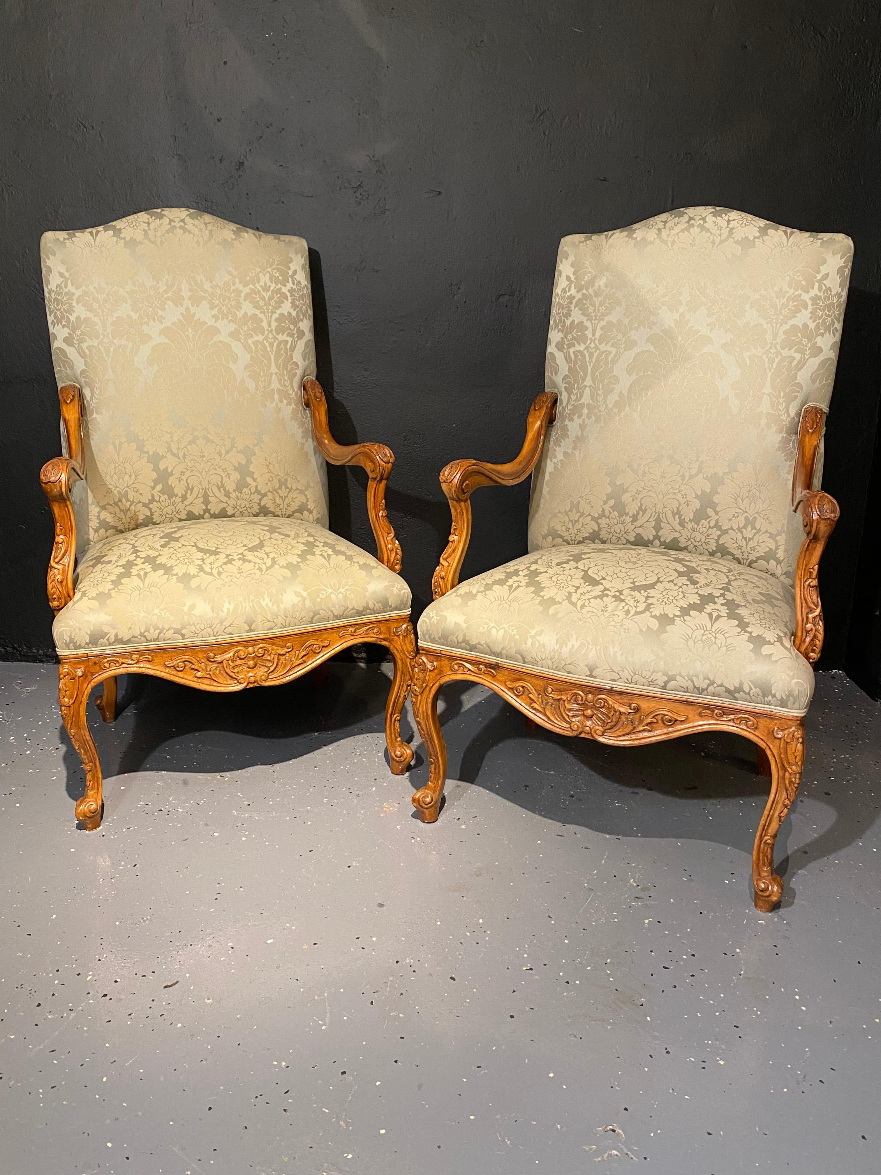 Louis XVI style antique arm, Throne chairs finely upholstered. A pair of stunning finely carved walnut framed and custom upholstered Throne chairs. Seemingly fit for a king and a queen are these clean and sharply upholstered chairs.
 