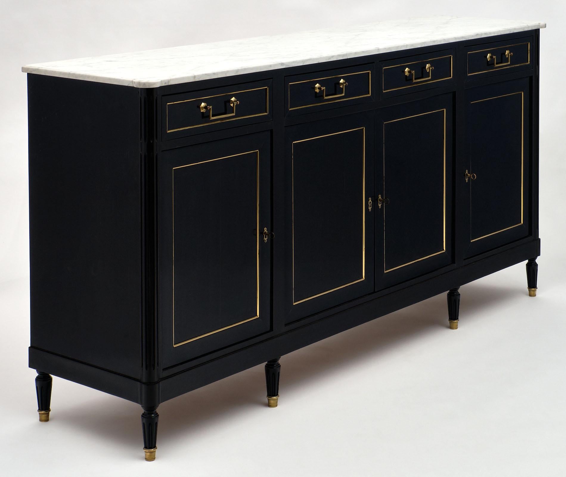 Antique Louis XVI style buffet made of ebonized solid mahogany with a lustrous French polish finish. The four drawers and doors are adorned with brass trims and original bronze hardware. The white Carrara marble top is original to the piece and