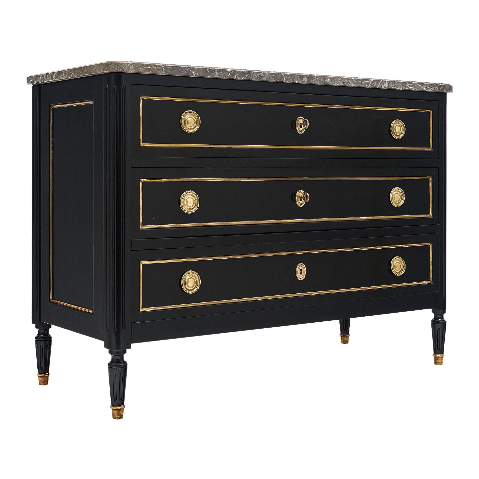 Chest of Drawers, French, in the Louis XVI style. This piece has three dovetailed drawers with brass trim and hardware throughout. The pulls and locks are in working condition. The piece is supported by four tapered feet capped in brass. The chest